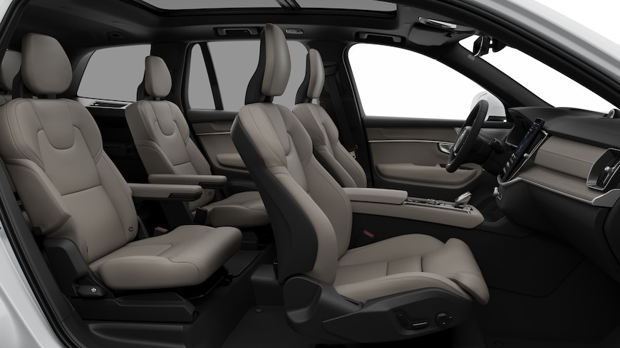 Volvo car interior side view showcasing front seats, rear passenger seats, steering wheel, dashboard, and center console, set against plain studio background.
