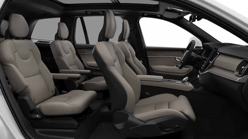 Volvo car interior side view showcasing front seats, rear passenger seats, steering wheel, dashboard, and center console, set against plain studio background.