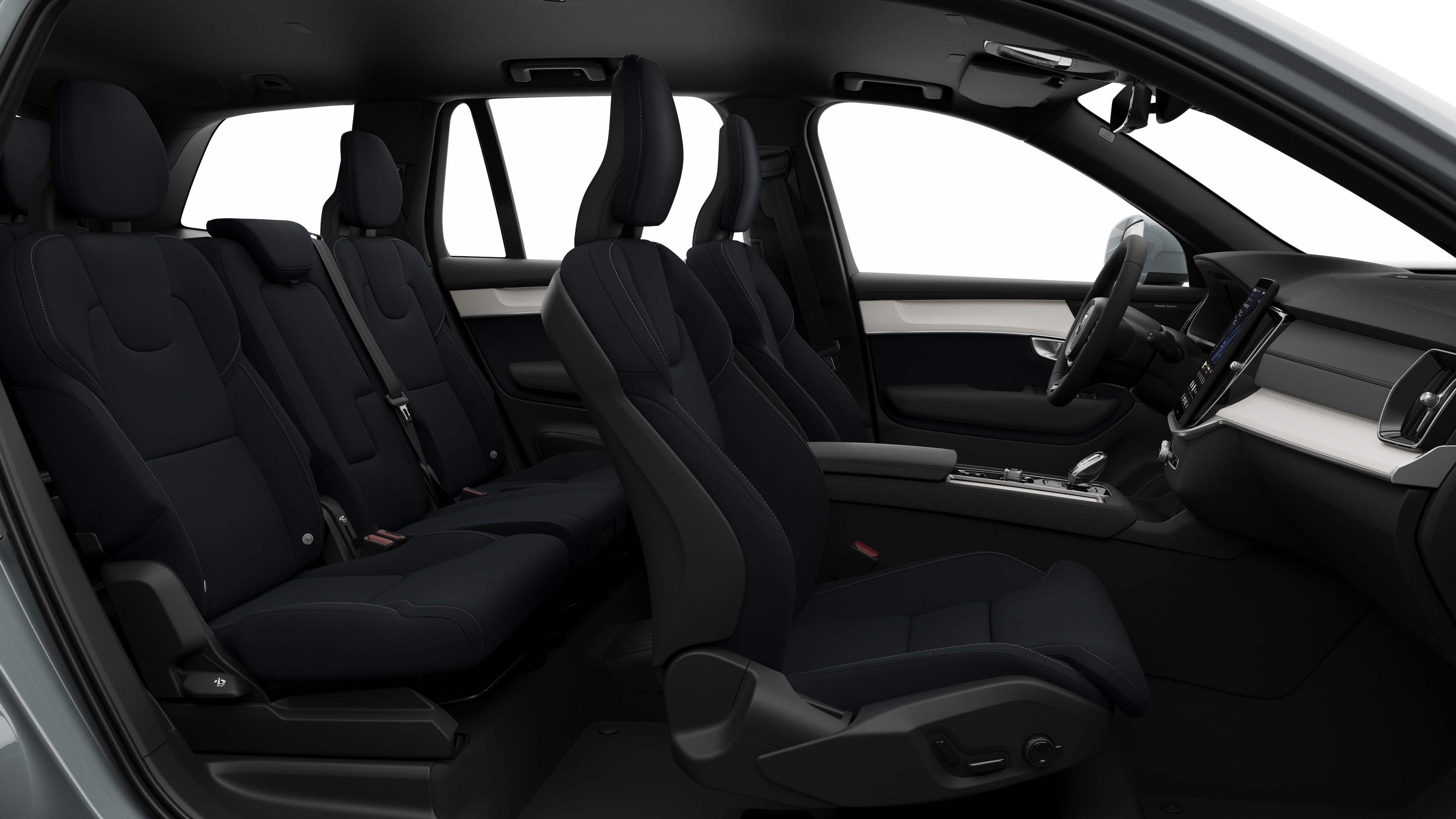 Zijaanzicht van het interieur van een Volvo met de voorstoelen, de passagiersstoelen achterin, het stuur, het dashboard en de middenconsole, tegen een effen studioachtergrond.