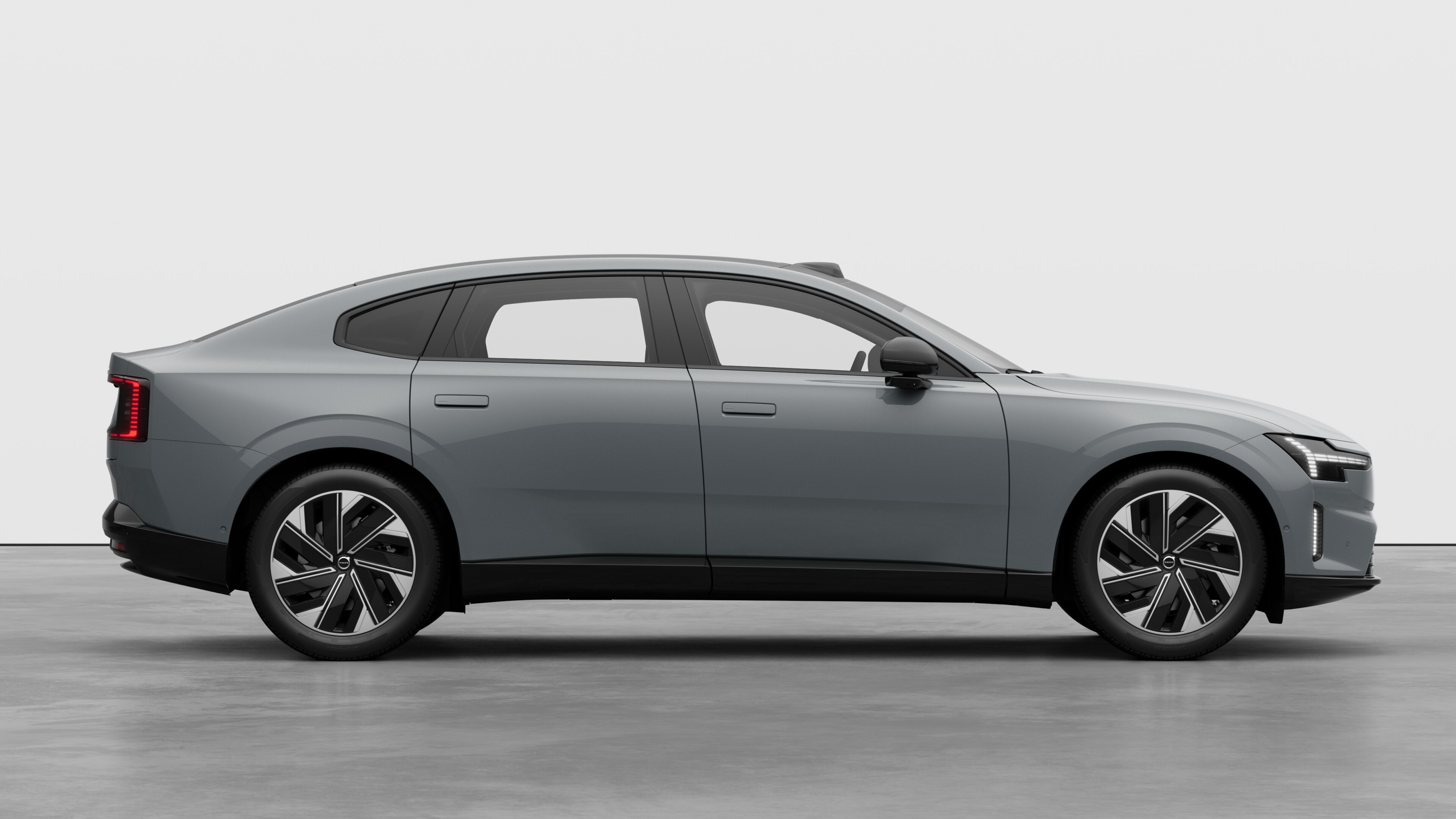 Страничен изглед на автомобил Volvo на обикновен студиен фон, показващ затворени врати и видим дизайн на колелата.