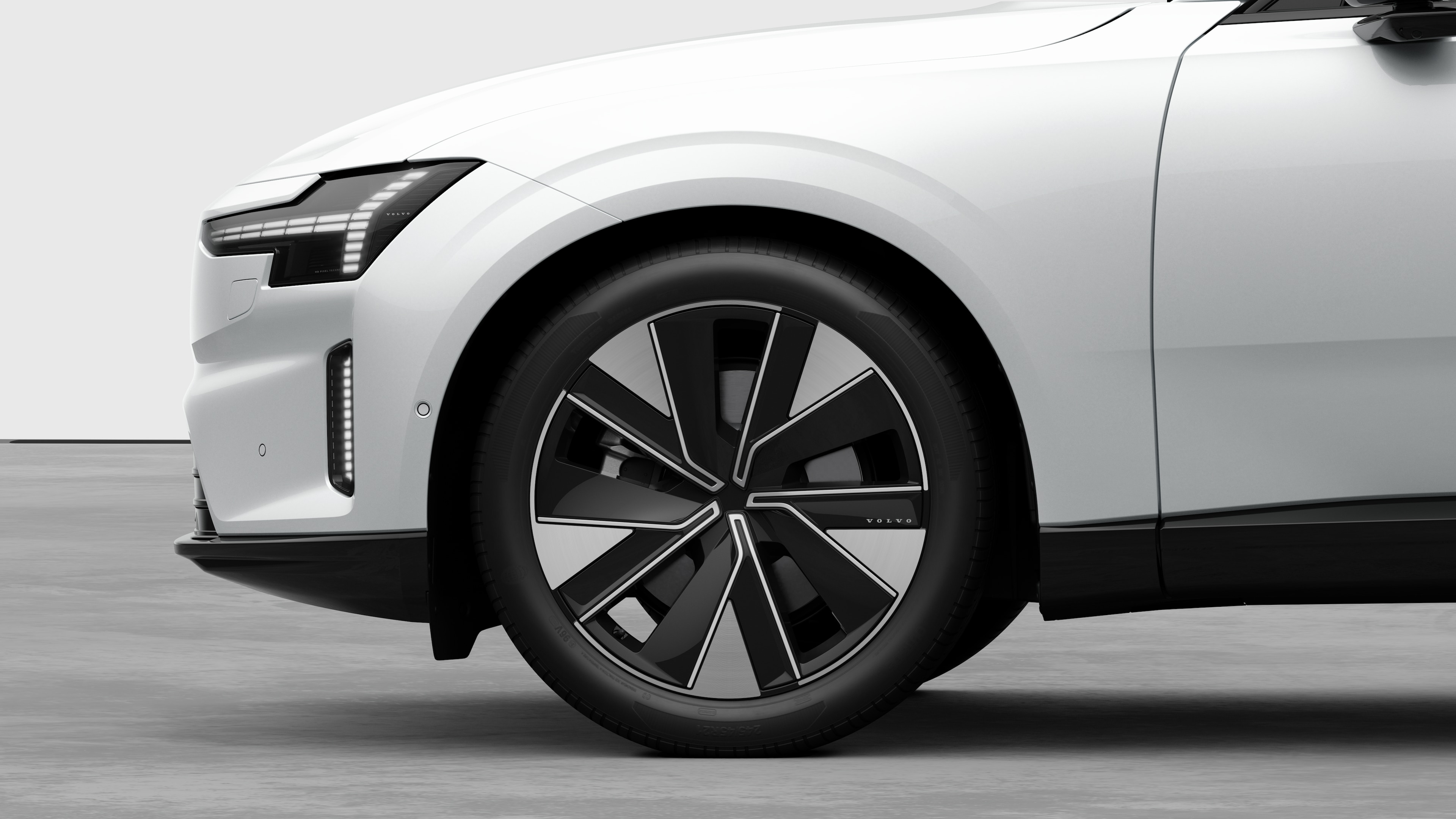 Volvo car exterior side view focusing on the front wheel and fender, set against a plain studio background.