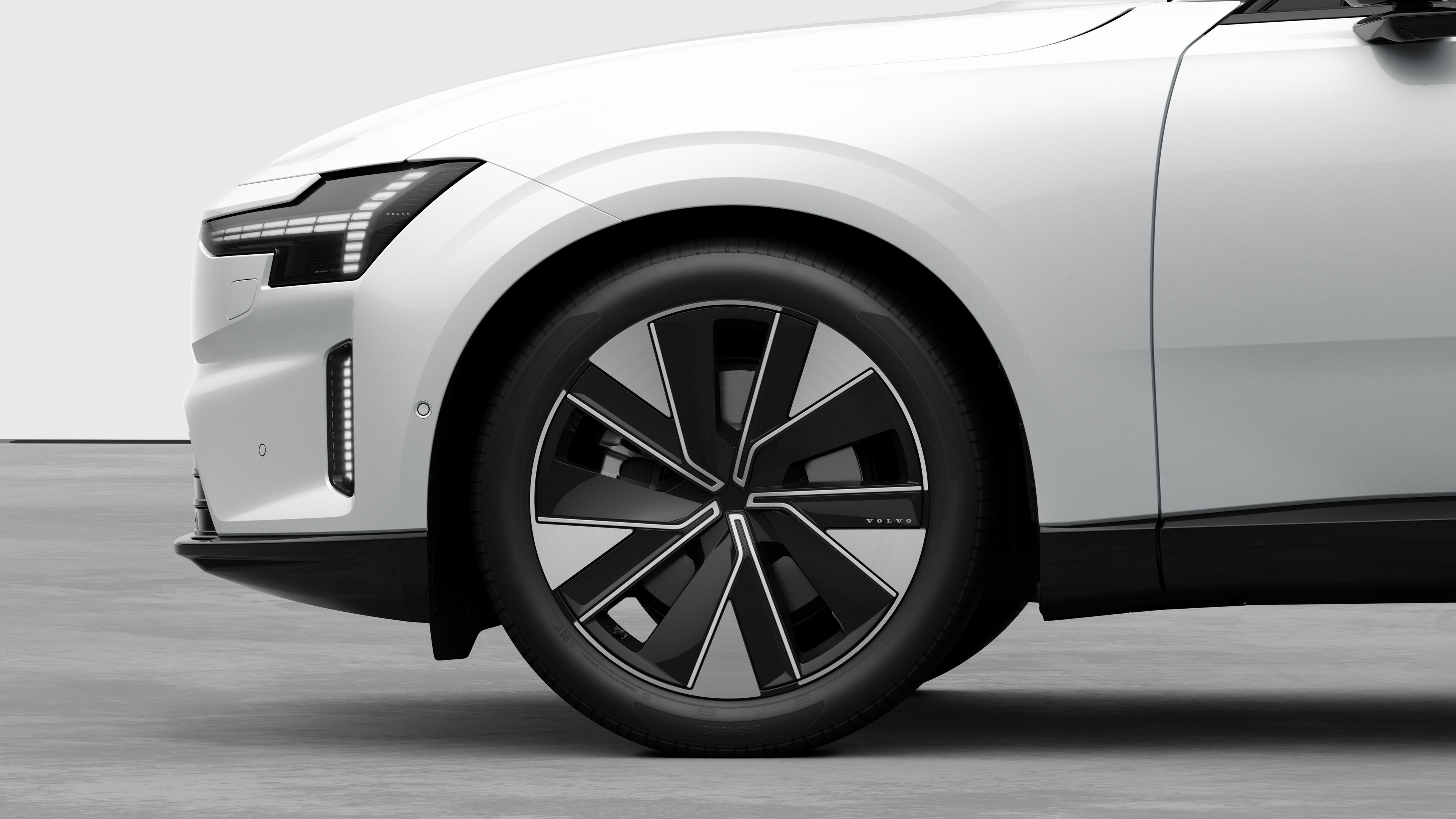 มุมมองภายนอกของรถยนต์วอลโว่เน้นที่ล้อหน้าและบังโคลน ซึ่งตัดกับพื้นหลังของสตูดิโอแบบเรียบๆ
