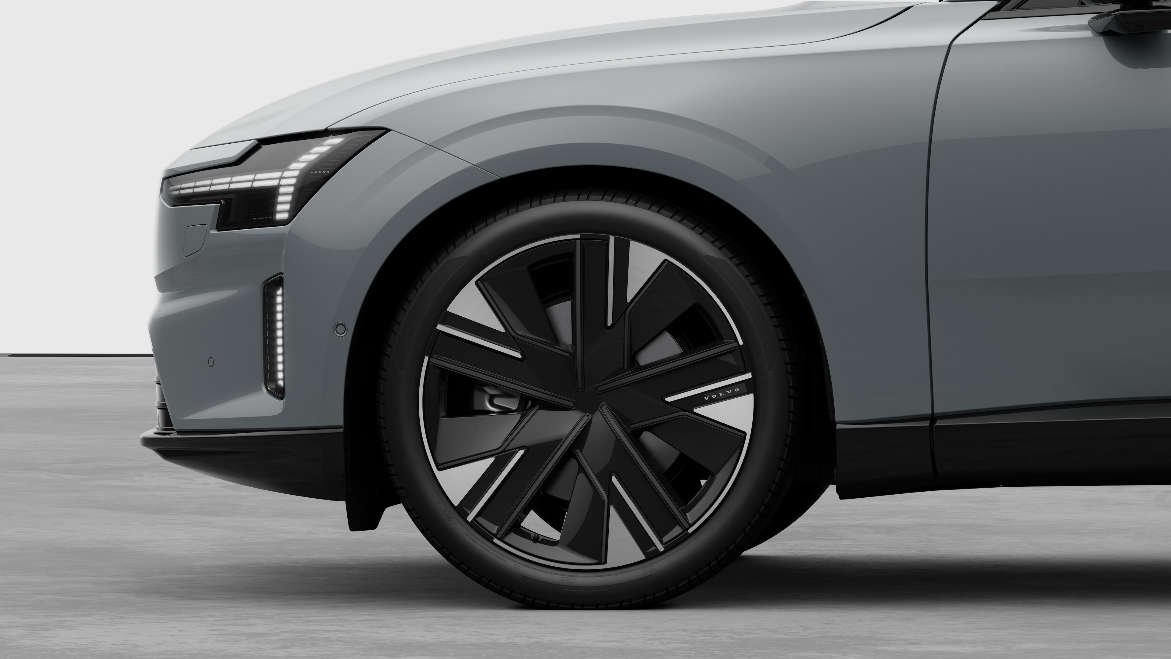 Volvo car exterior side view focusing on the front wheel and fender, set against a plain studio background.