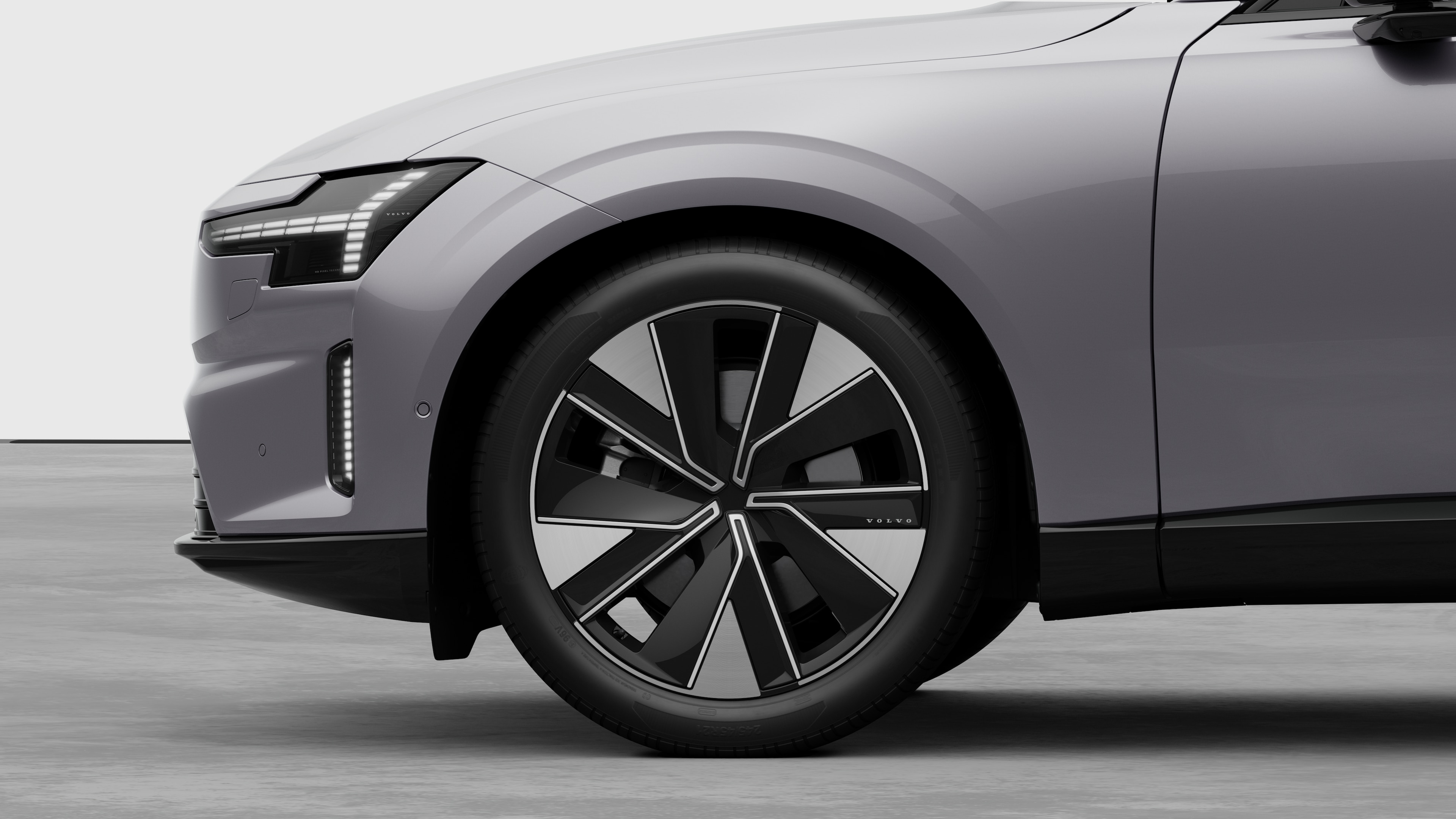 มุมมองภายนอกของรถยนต์วอลโว่เน้นที่ล้อหน้าและบังโคลน ซึ่งตัดกับพื้นหลังของสตูดิโอแบบเรียบๆ