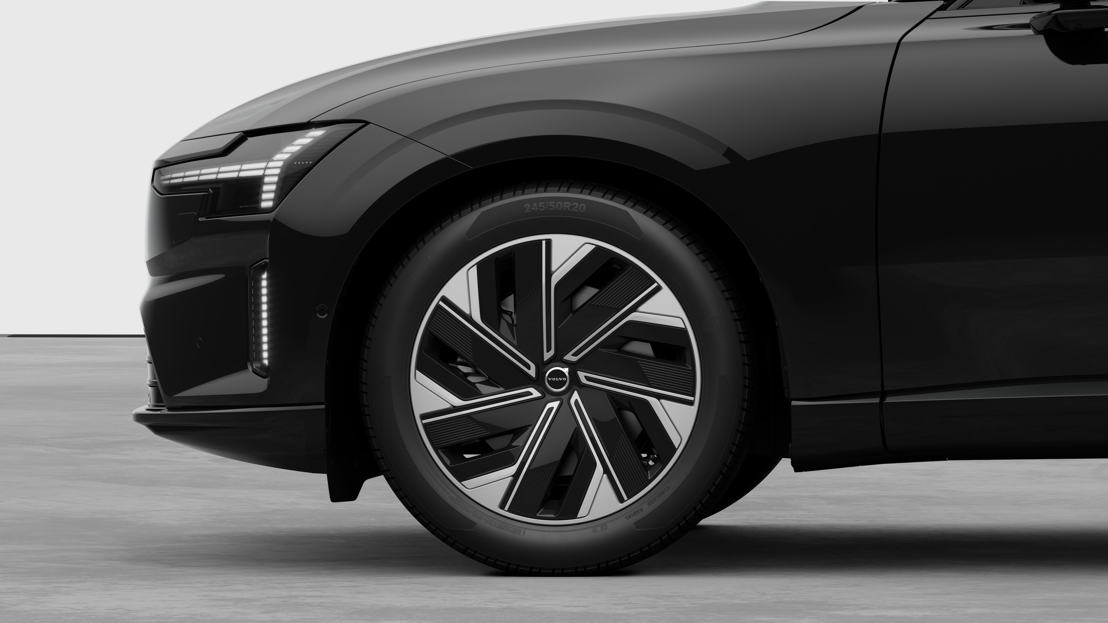 Volvo car exterior side view focusing on the front wheel and fender, set against a plain studio background.