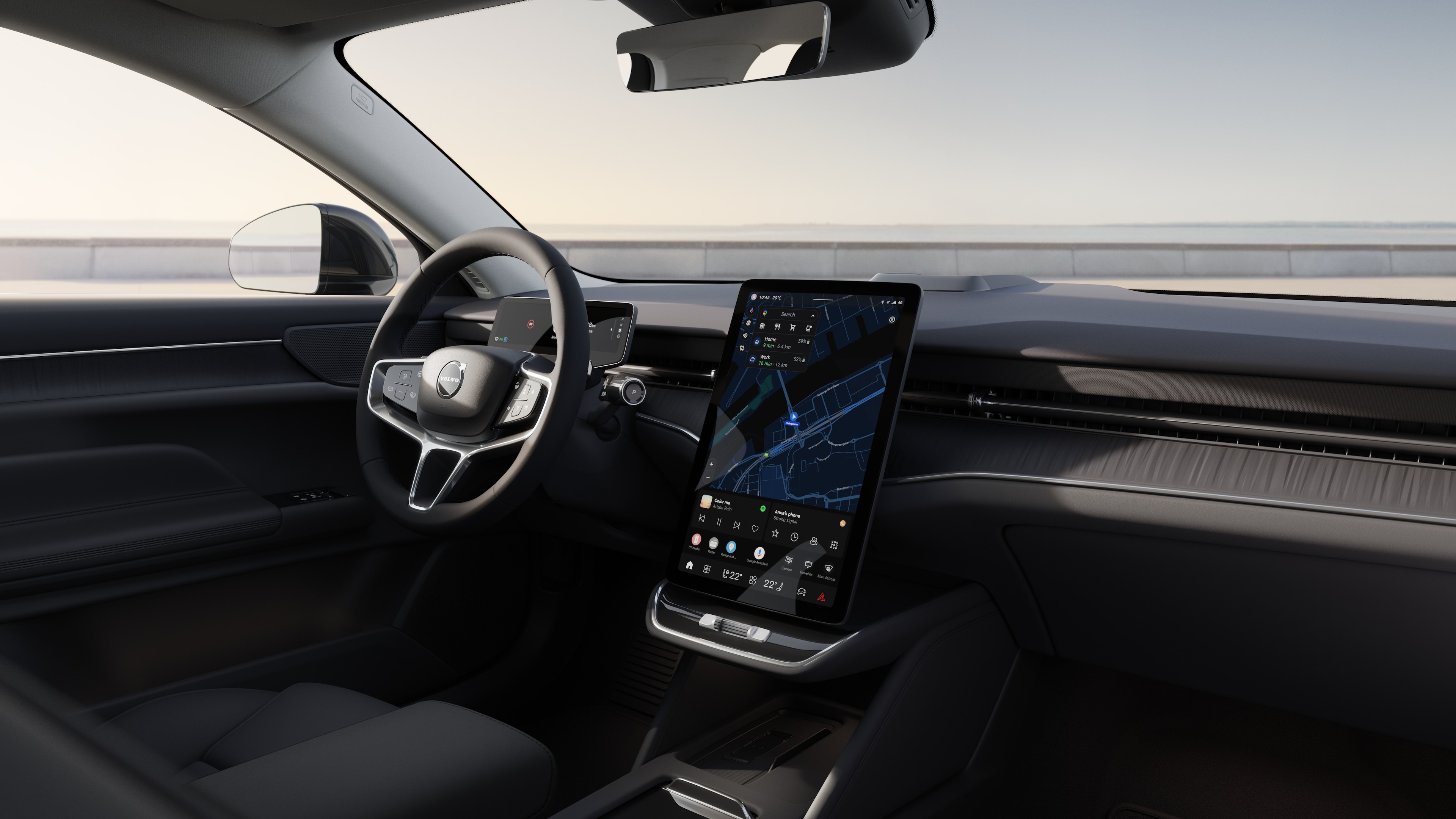 Wnętrze samochodu Volvo z deską rozdzielczą, kierownicą i konsolą środkową z cyfrowym wyświetlaczem na otwartym tle drogi.