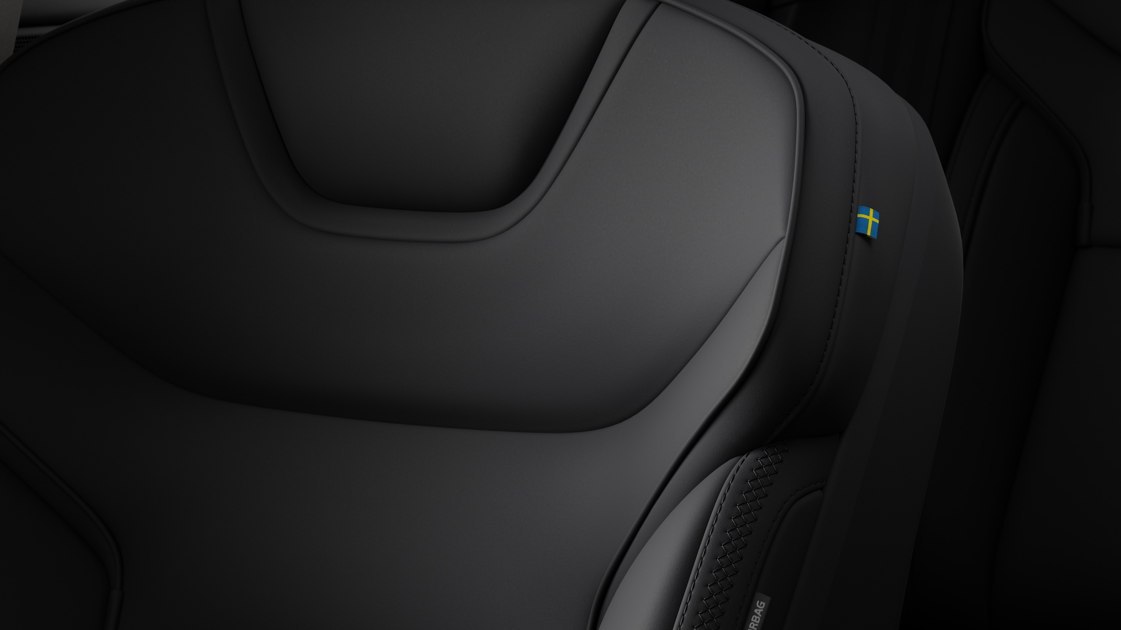 Close-up van een detail van de zetel in het interieur van een Volvo met stiksels en een klein Zweeds vlaglabel.