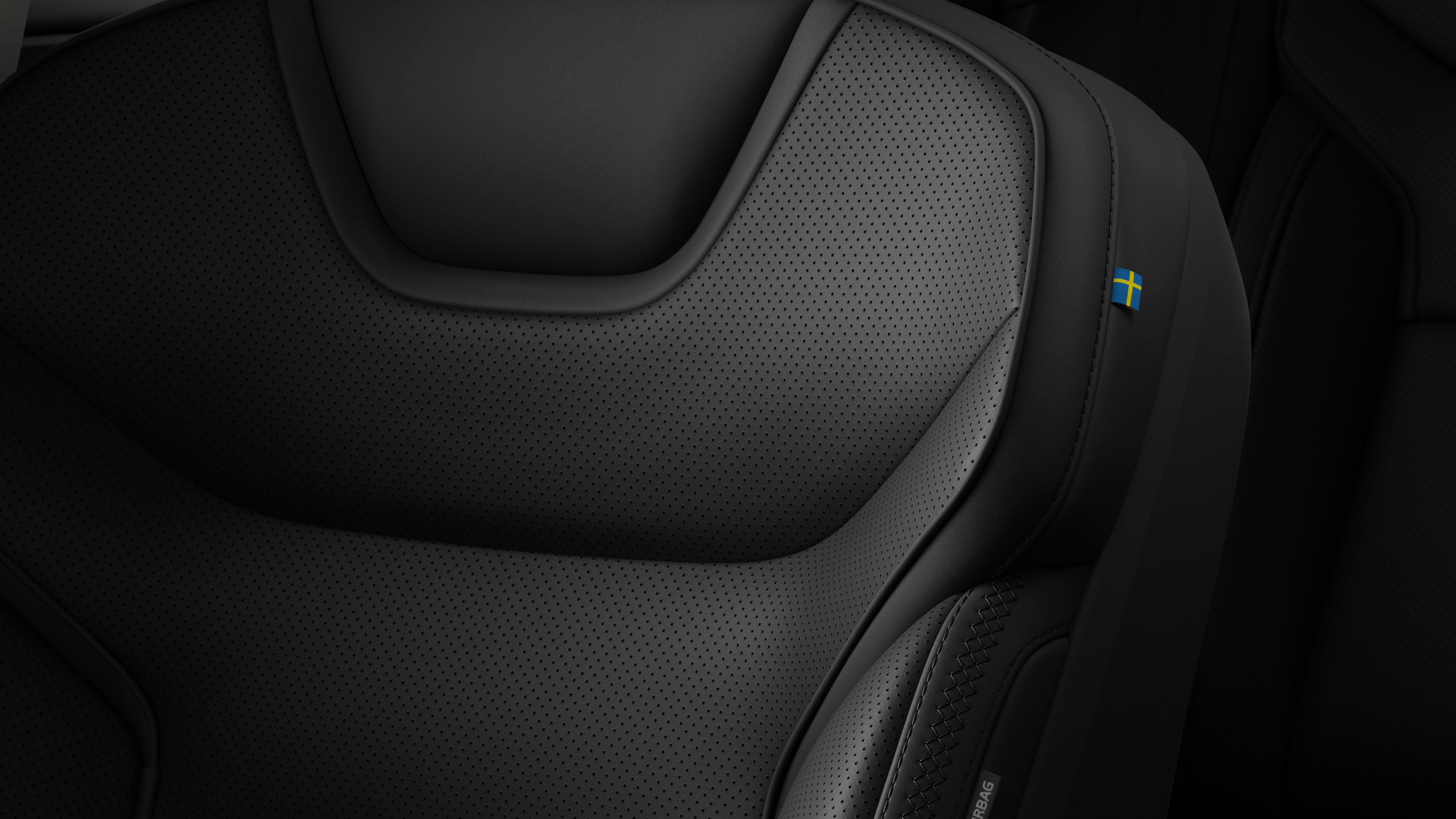 Close-up van het detail van het interieur van een Volvo-autostoel met stiksels en een klein Zweeds vlaglabel.