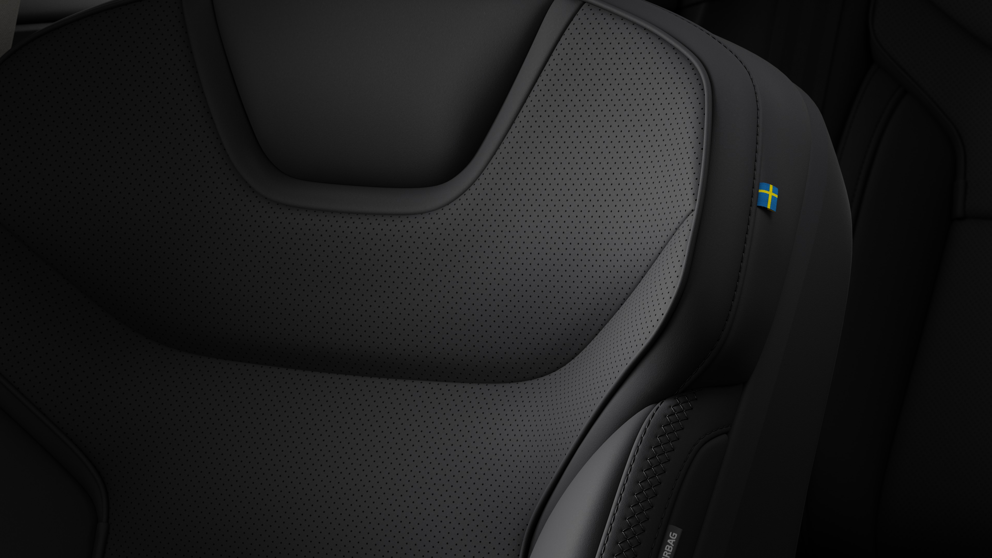 Close-up of Volvo car interior seat detail showing stitching and a small Swedish flag tag.