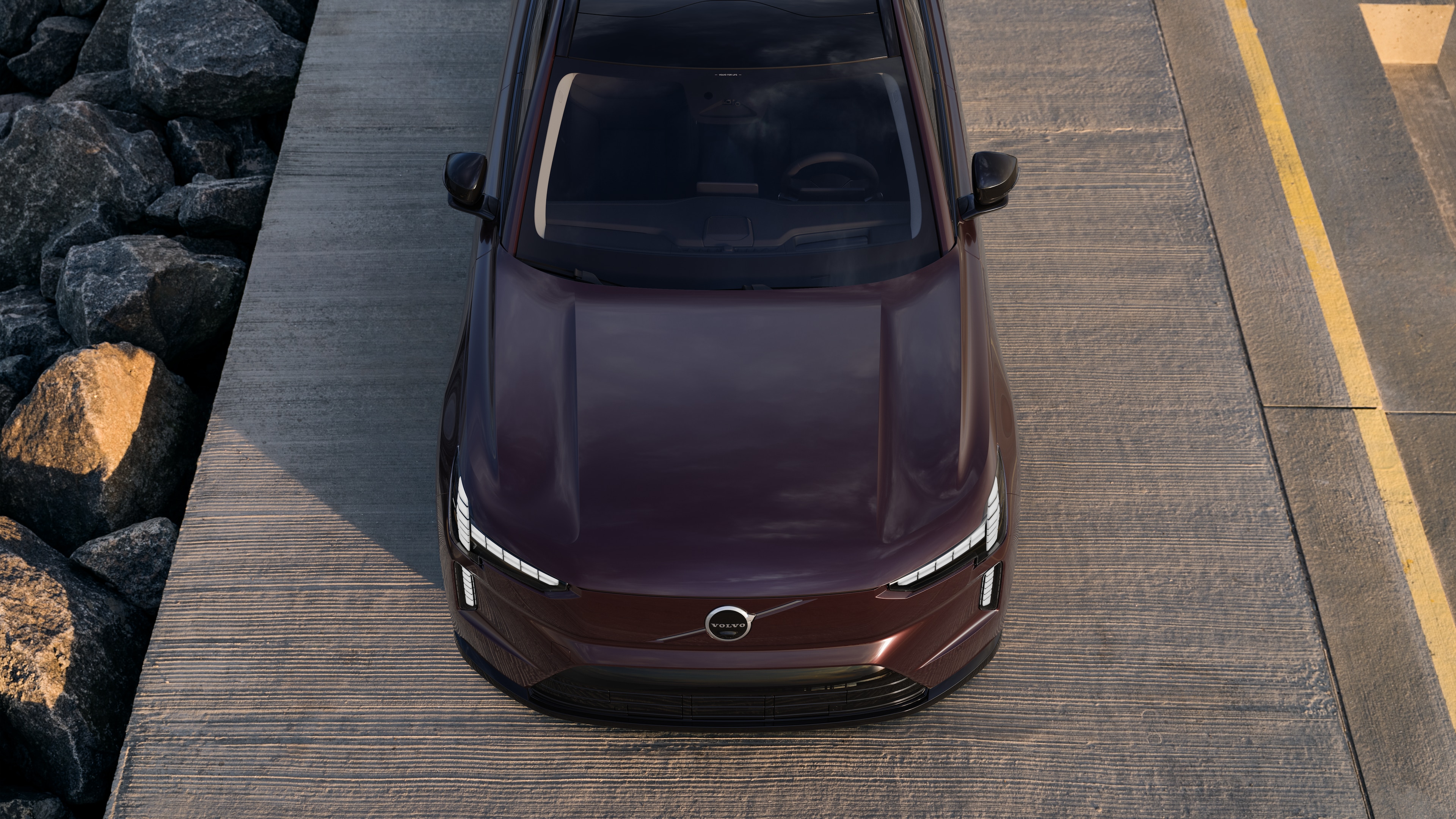 Volvo automašīnas ārpuse trīs ceturtdaļu skatā uz pilsētas ielas fona, parādot vienu pusi, jumtu un daļu priekšpuses.