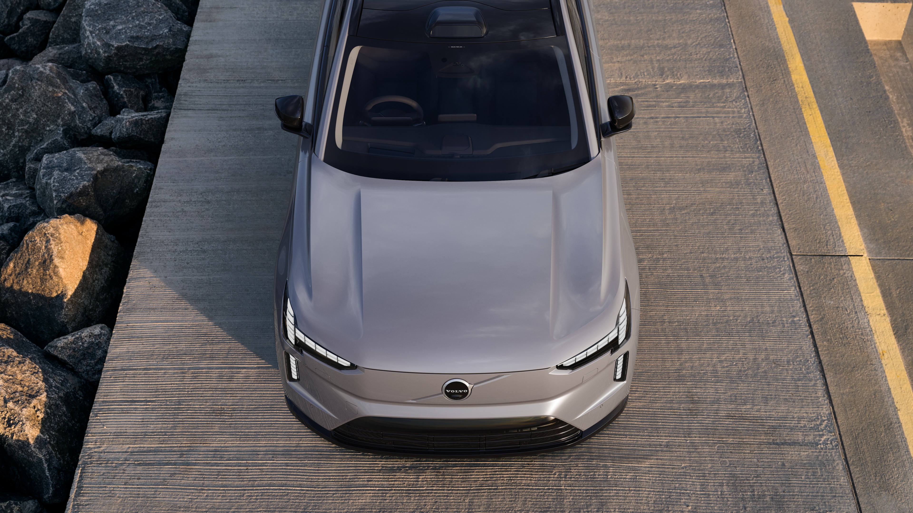 Volvo car exterior in three-quarter view on an urban street background, showing one side, roof, and part of the front.