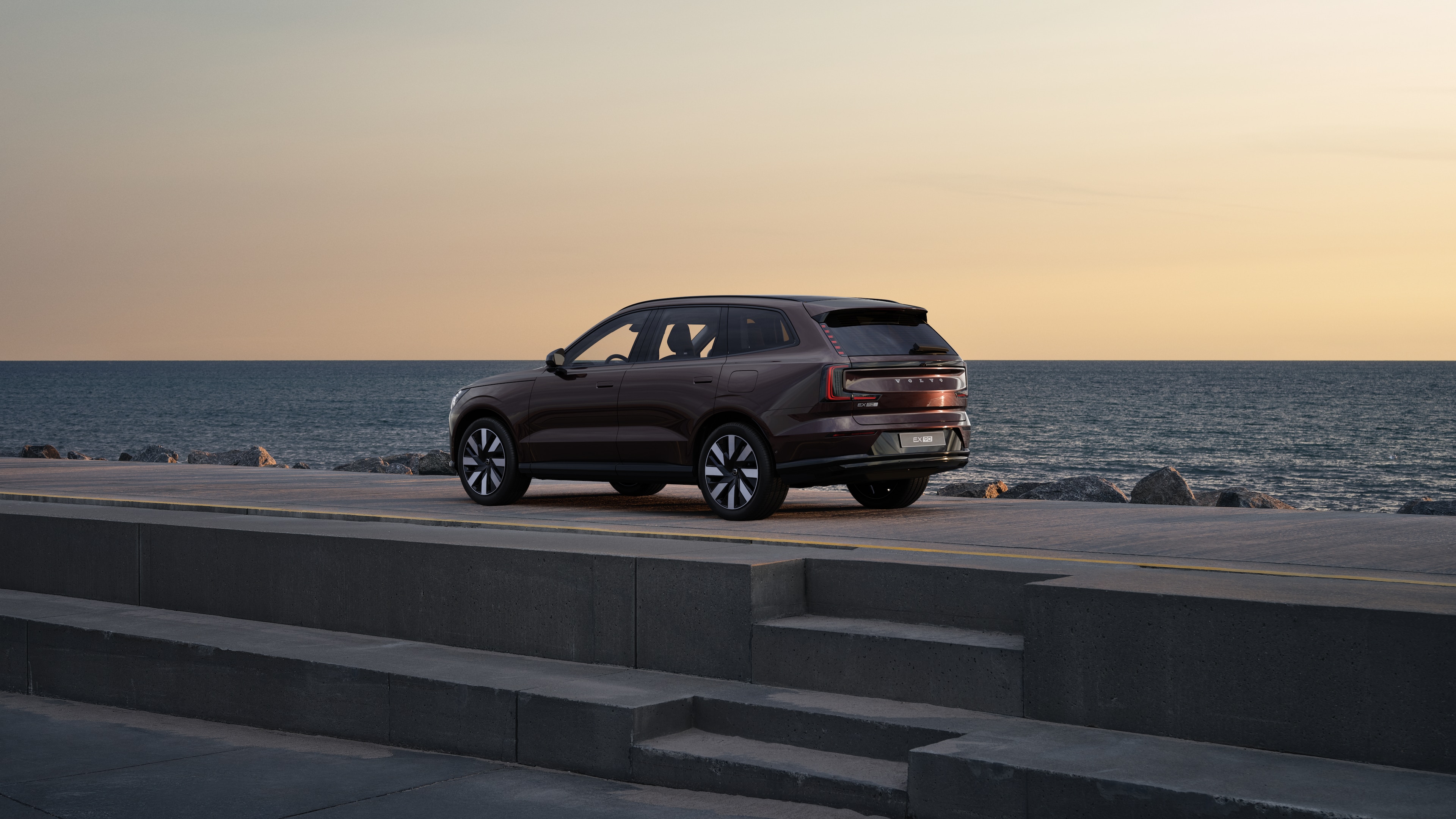 En Volvo i bakre trekvartsvy parkerad mot en betongvägg på en urban gata.