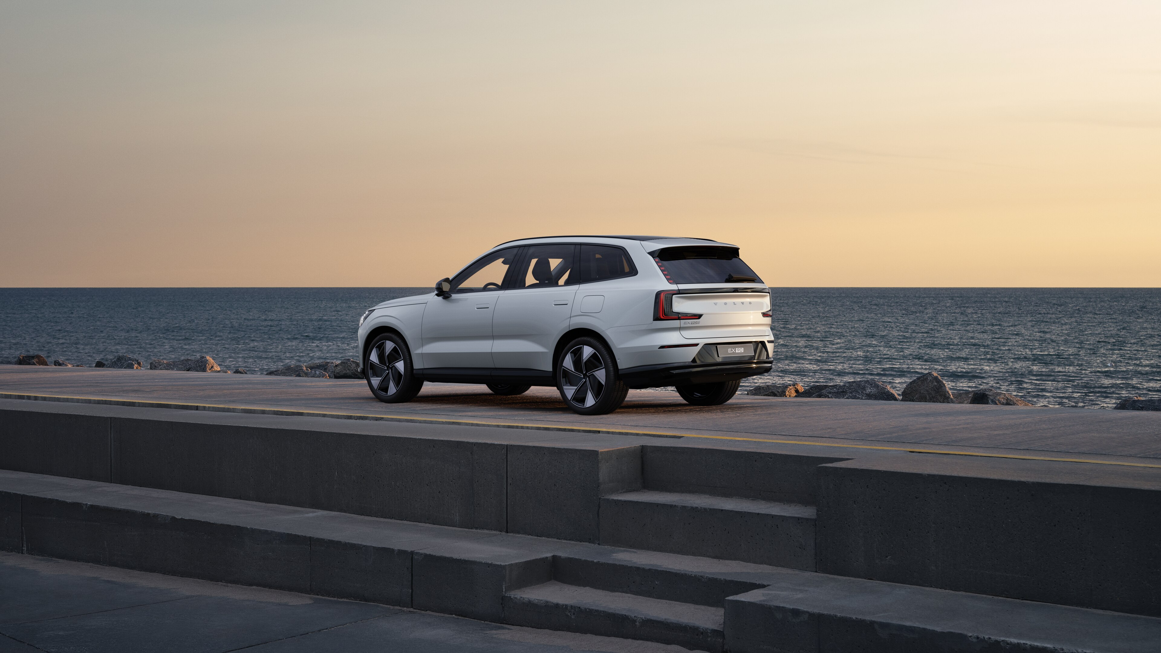 En Volvo i bakre trekvartsvy parkerad mot en betongvägg på en urban gata.