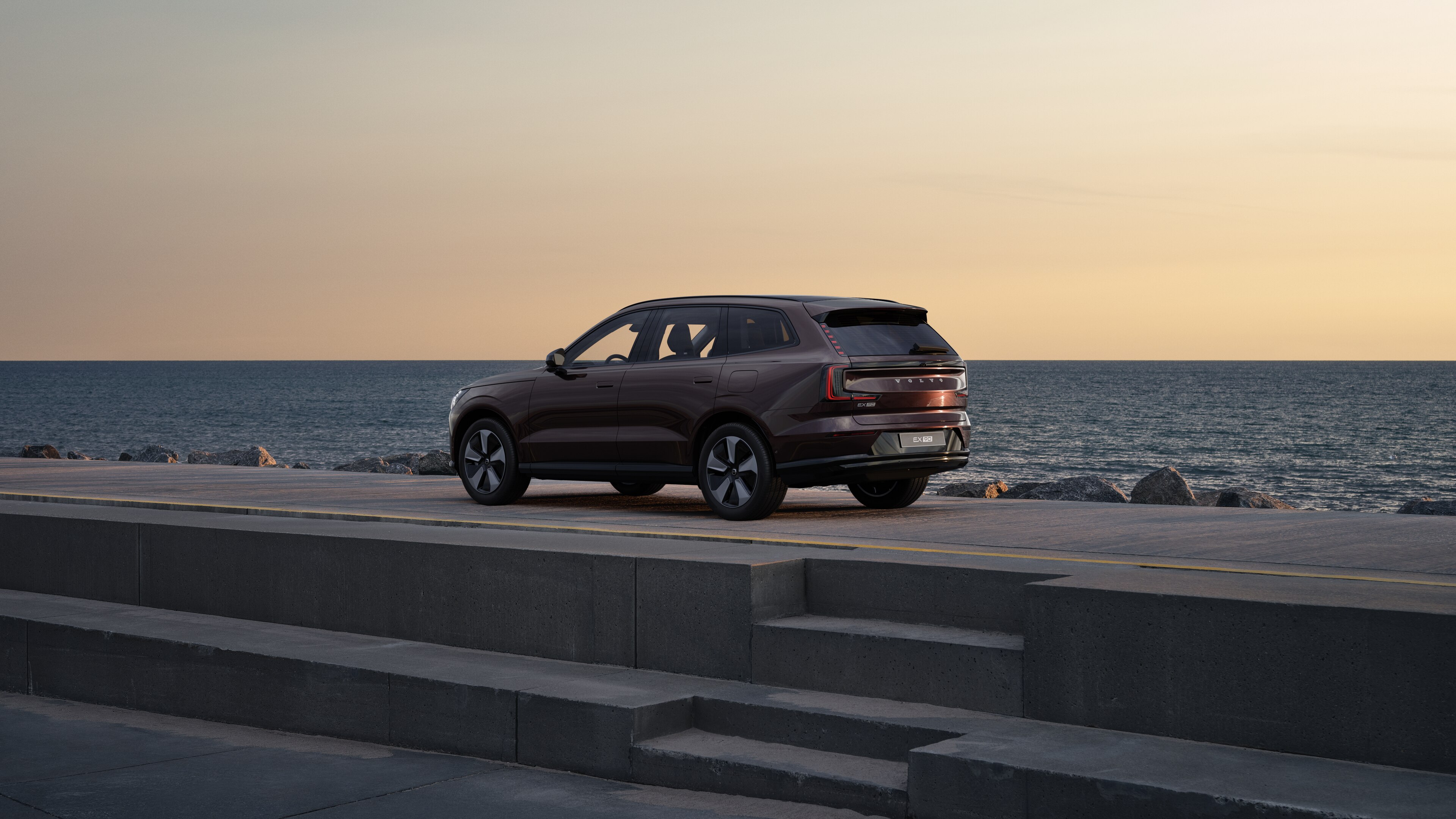 Volvo en vue arrière de trois quarts, garée contre un mur en béton dans une rue urbaine.
