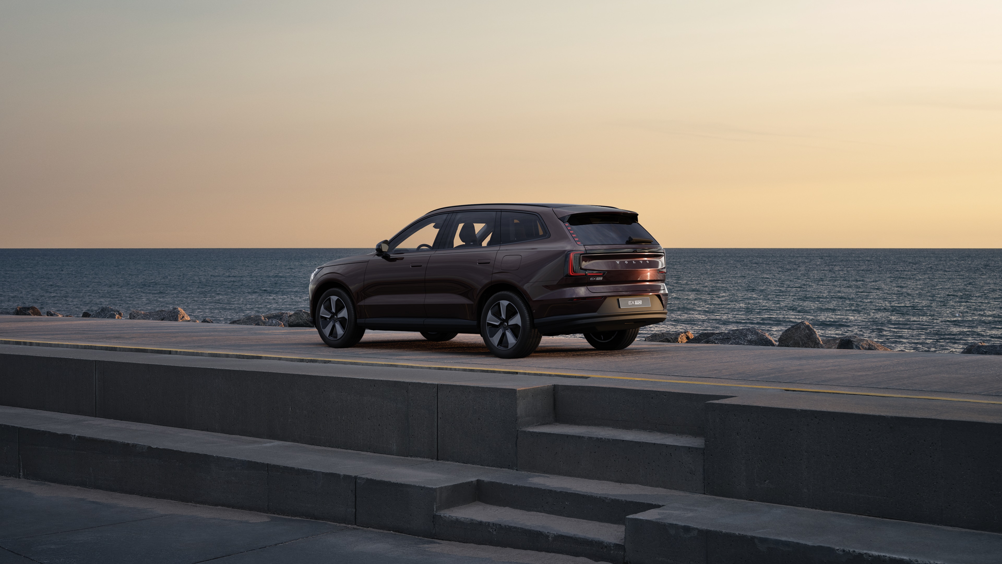 Voiture Volvo en vue arrière de trois quarts, garée contre un mur en béton sur un fond de rue urbaine.