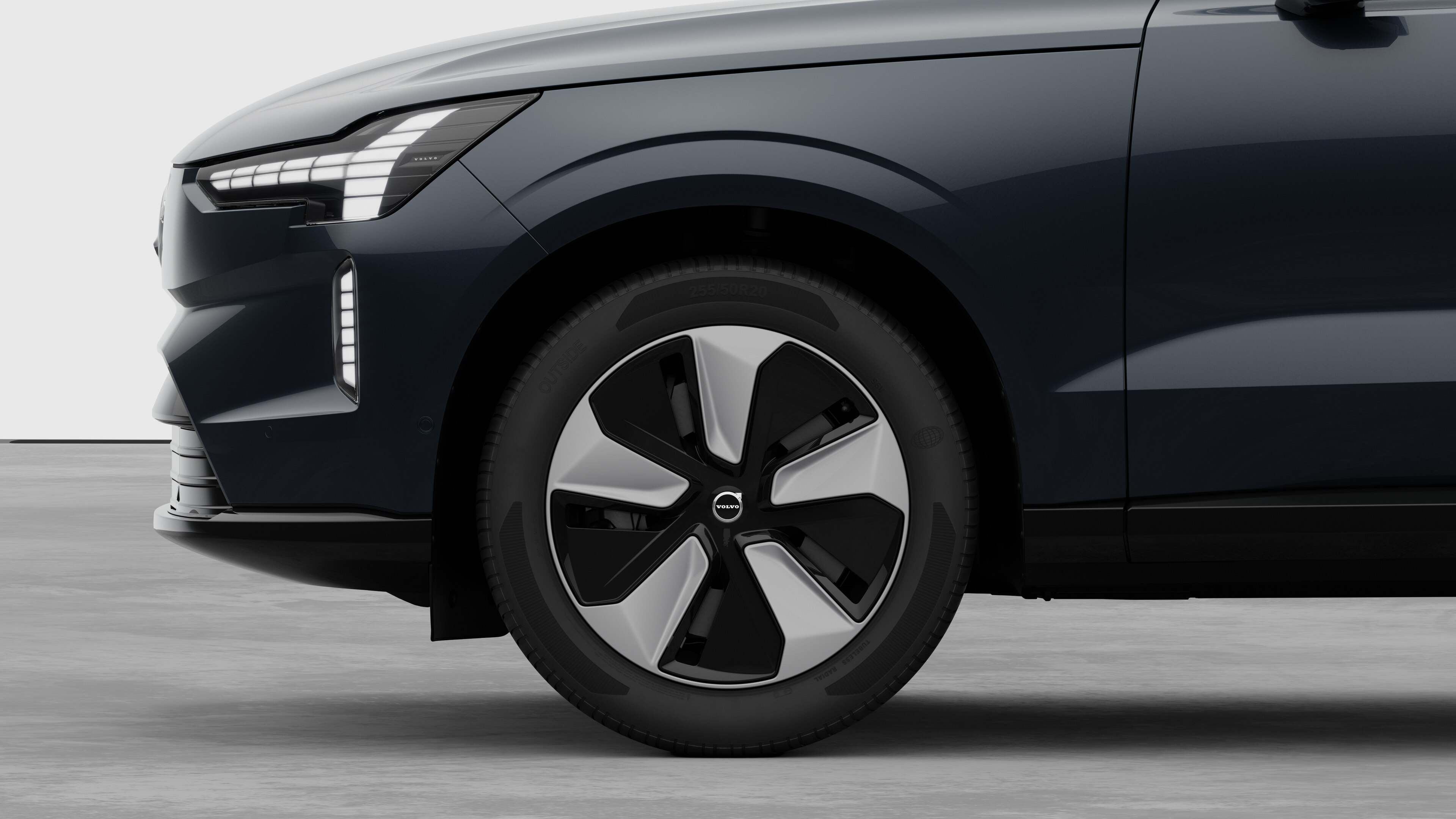 Vista laterale esterna di una Volvo con focus sulla ruota anteriore e sul parafango, su uno sfondo semplice in studio.