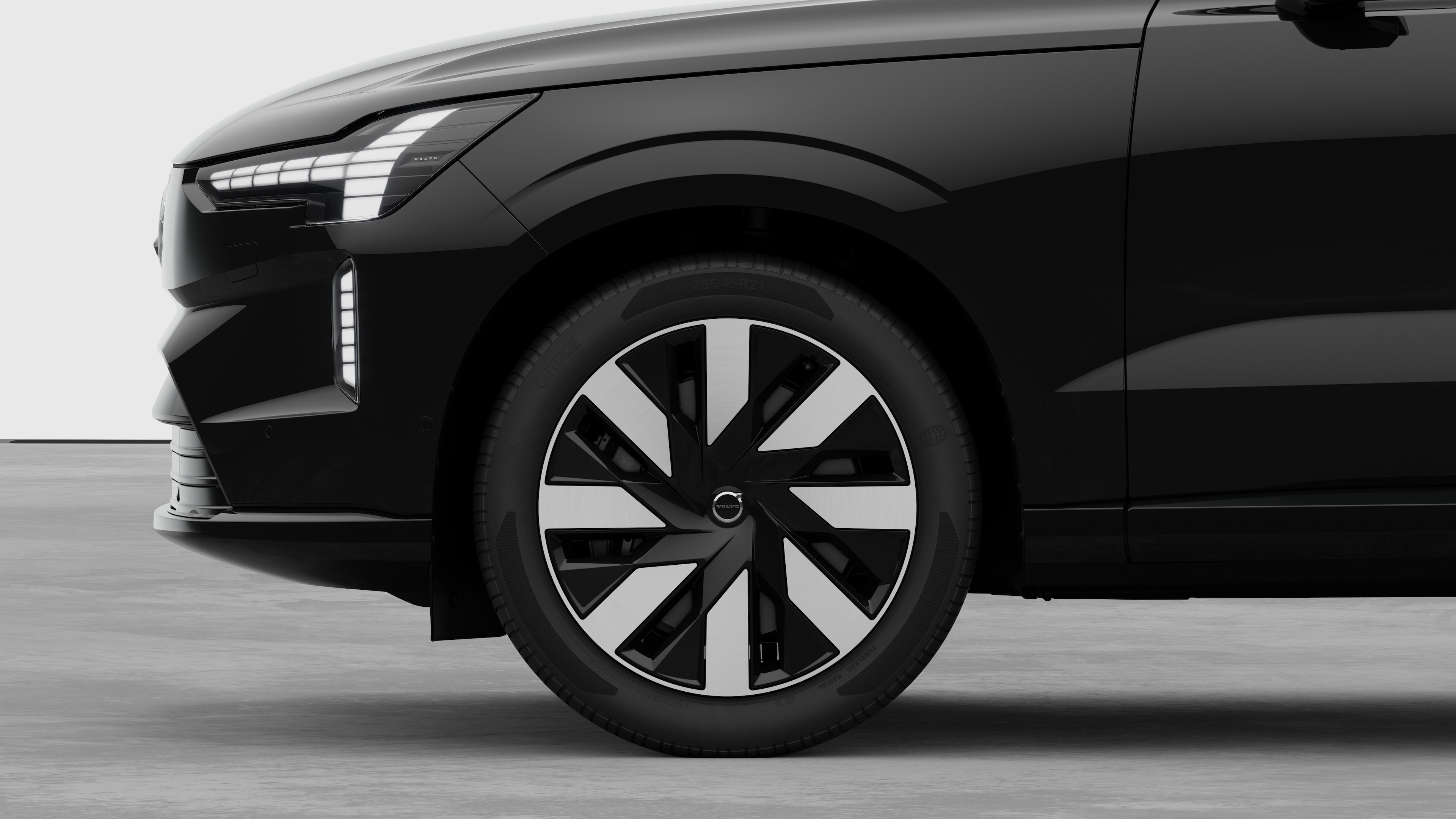 Vista laterale esterna di una Volvo con focus sulla ruota anteriore e sul parafango, su uno sfondo semplice in studio.