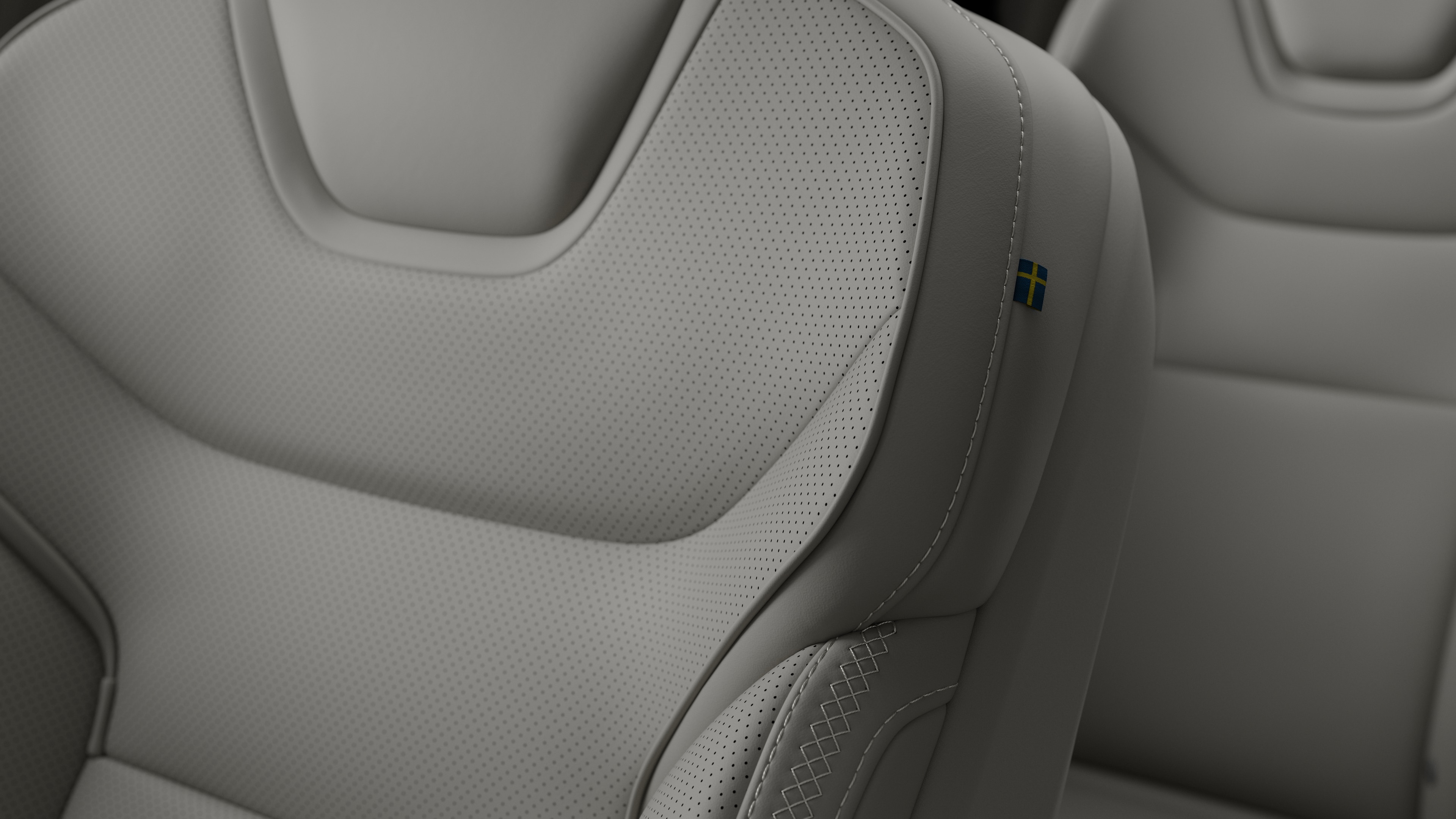 Närbild av Volvo Cars interiör, sätesdetalj som visar sömmar och en liten svensk flagga.