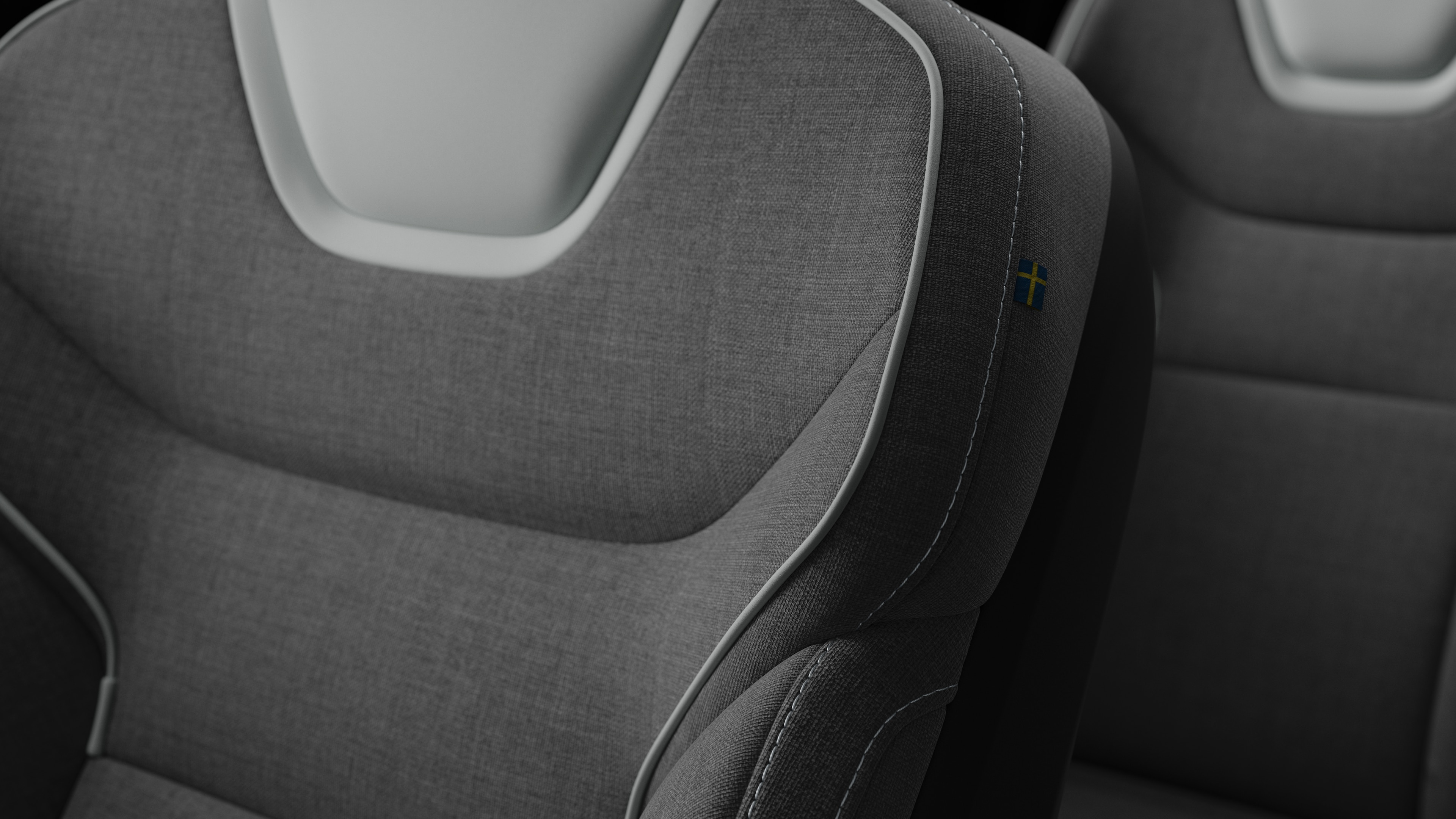 Närbild av Volvo Cars interiör, sätesdetalj som visar sömmar och en liten svensk flagga.