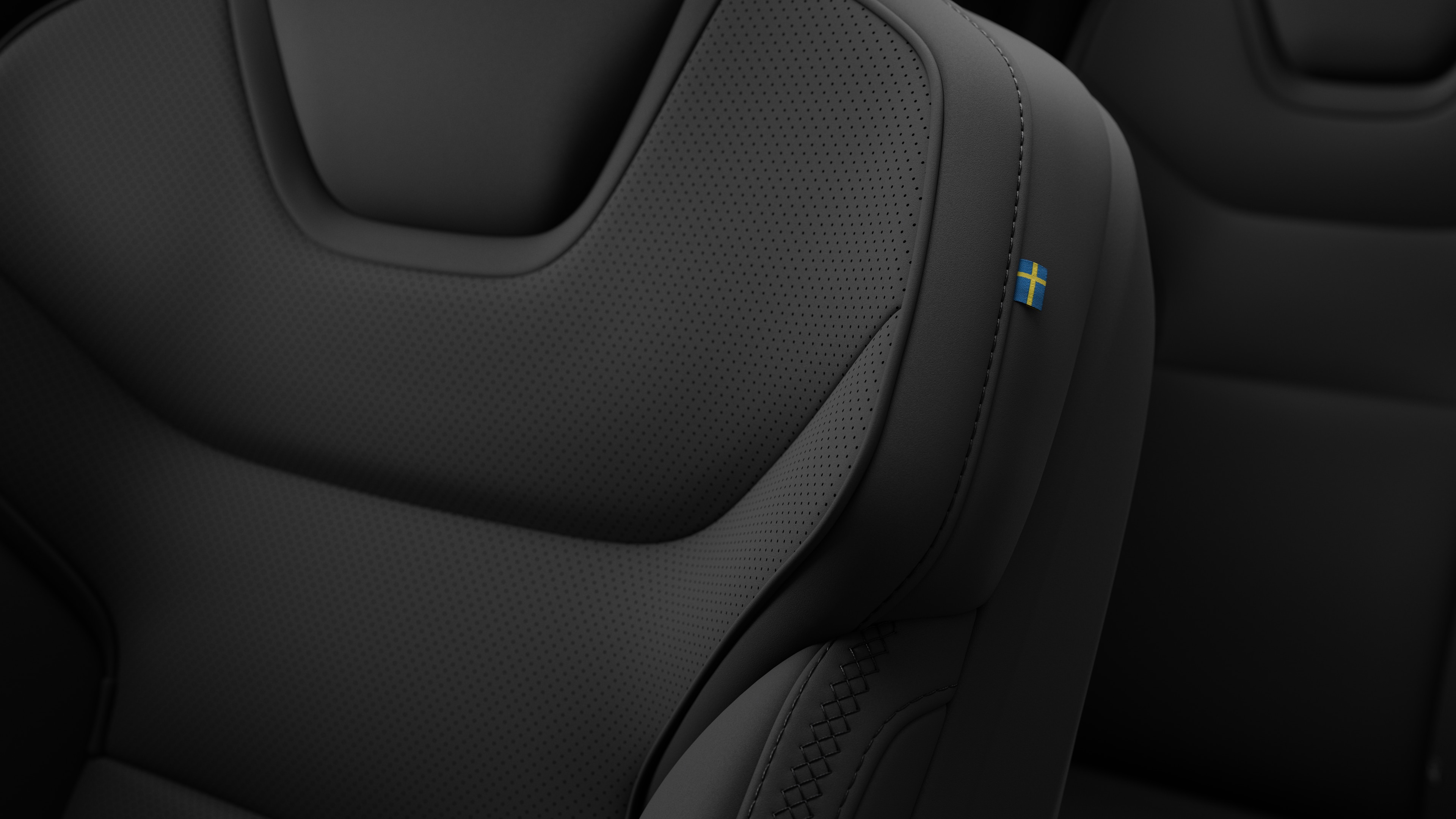 Närbild av Volvo Cars interiör, sätesdetalj som visar sömmar och en liten svensk flagga.