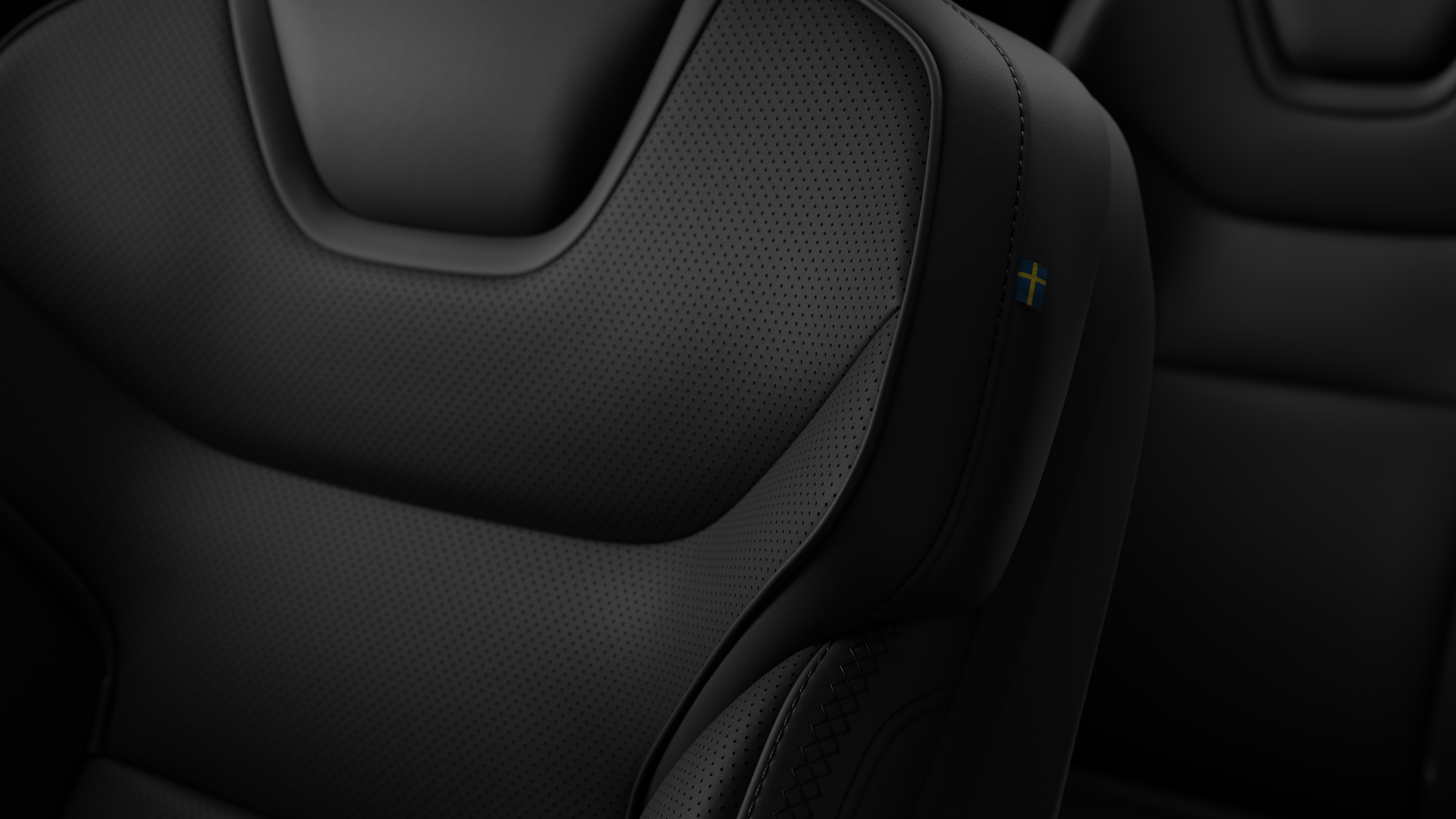 Närbild av Volvo Cars interiör, sätesdetalj som visar sömmar och en liten svensk flagga.