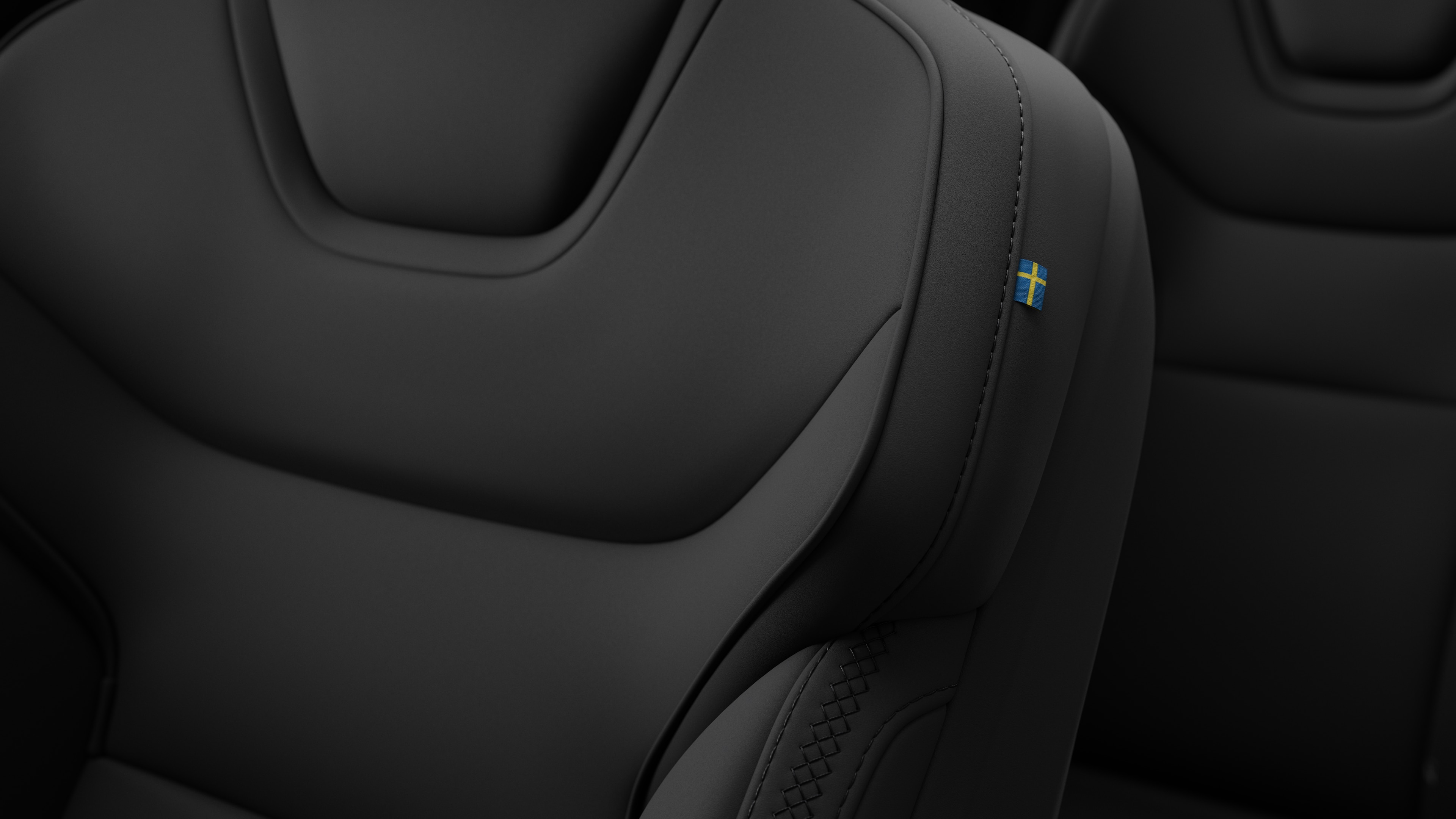 Detalle del asiento interior de un coche Volvo en el que se ven costuras y una pequeña etiqueta con la bandera sueca.