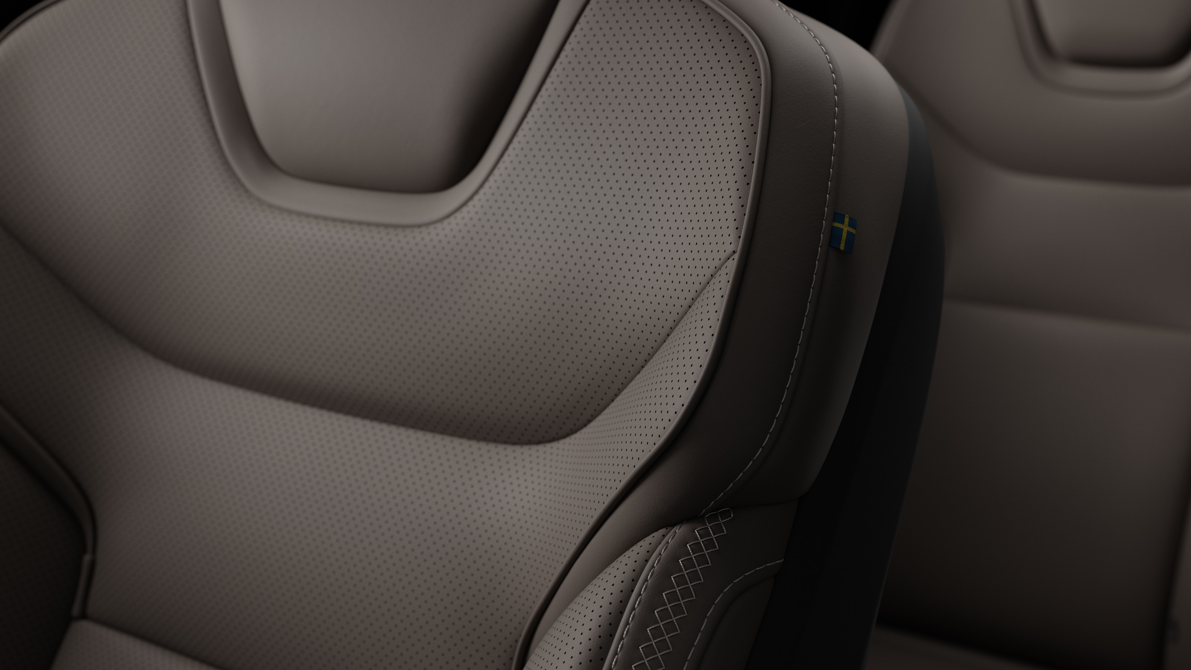 Detalle del asiento interior de un coche Volvo en el que se ven costuras y una pequeña etiqueta con la bandera sueca.