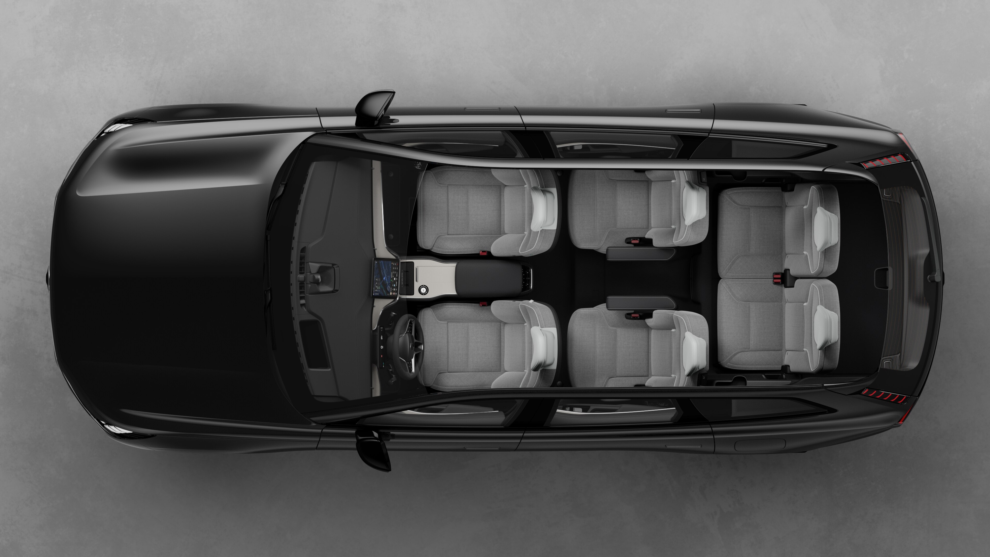 Bovenaanzicht van het interieur van een Volvo-auto, met twee rijen stoelen, dashboard en middenconsole, tegen een effen studioachtergrond.