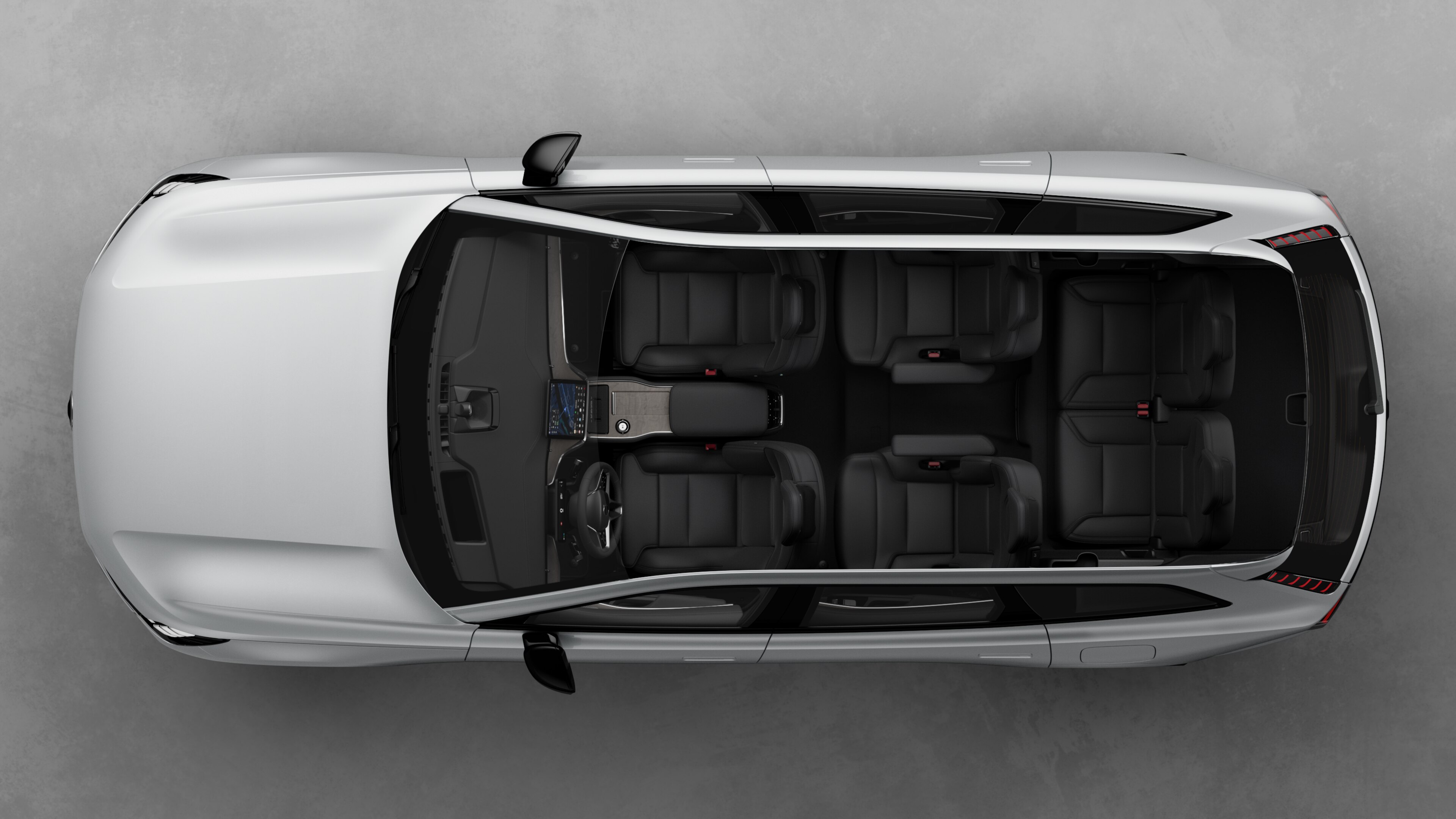 Bovenaanzicht van het interieur van een Volvo-auto, met twee rijen stoelen, dashboard en middenconsole, tegen een effen studioachtergrond.