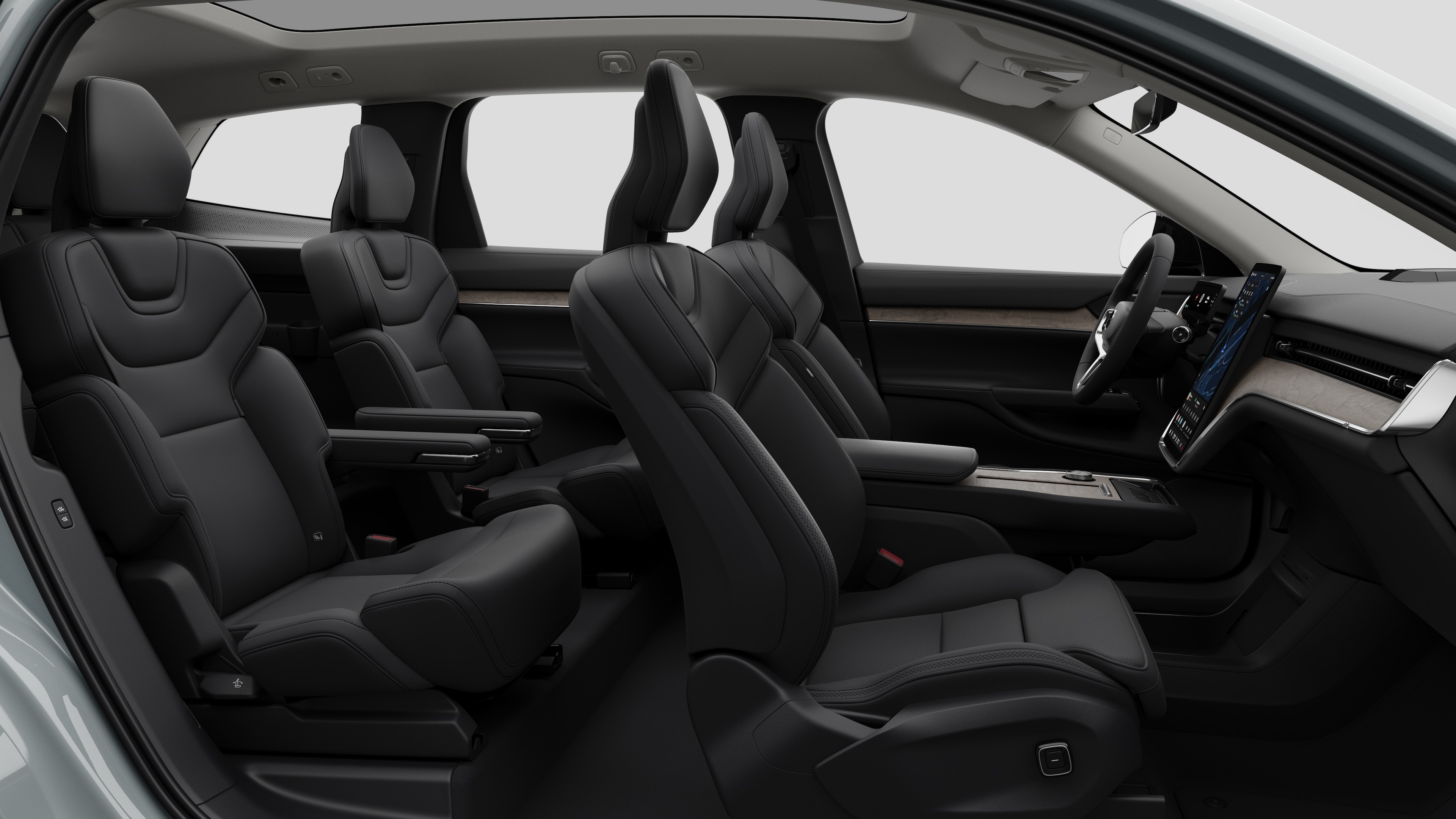 Widok z boku wnętrza samochodu Volvo z przednimi fotelami, tylnymi siedzeniami pasażera, kierownicą, deską rozdzielczą i konsolą środkową na tle zwykłego studia.