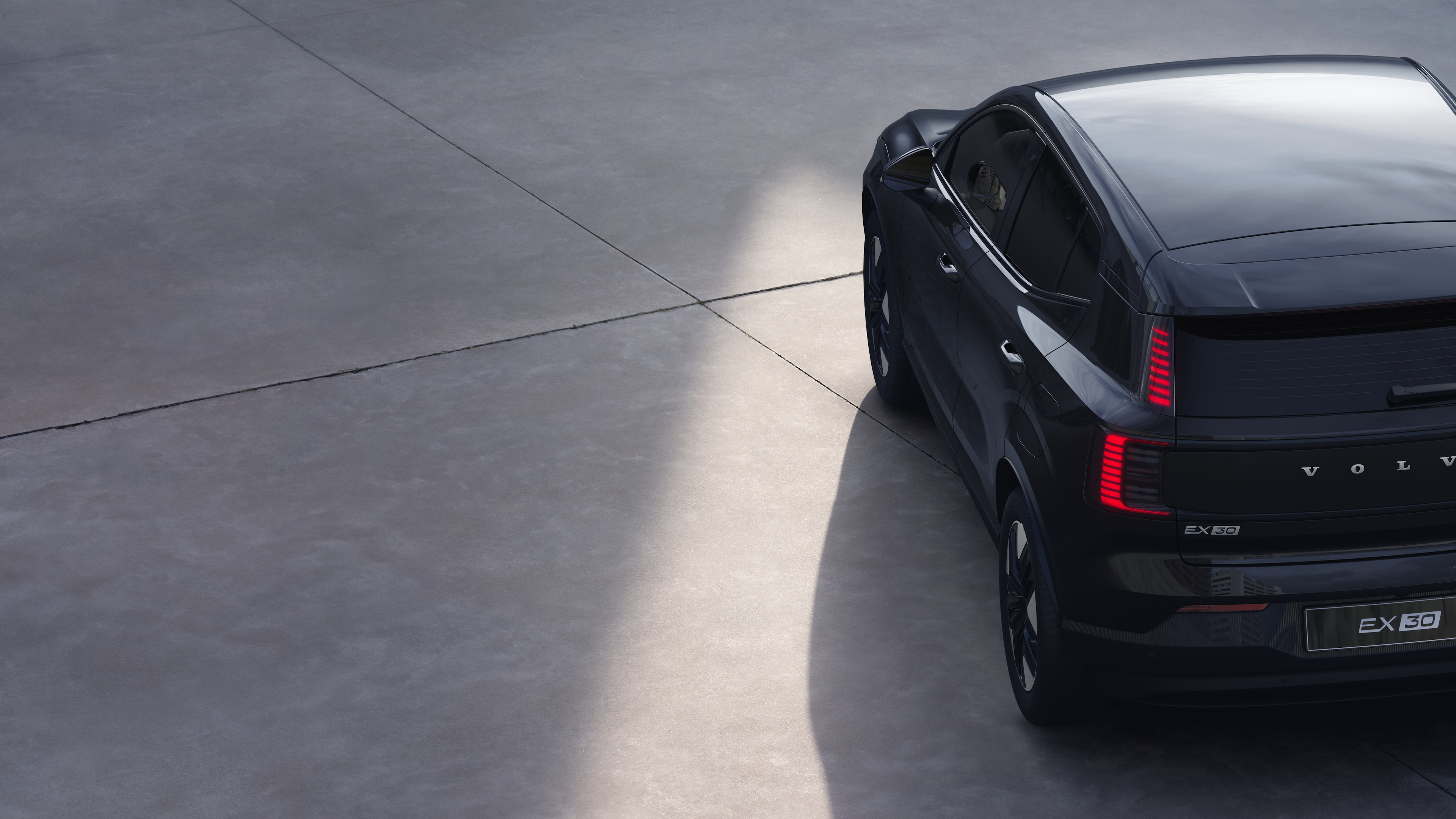 Driekwart achteraanzicht van een Volvo op een effen studioachtergrond, met het ontwerp van de achterlichten en de achterruitstructuur voor details aan de buitenkant.