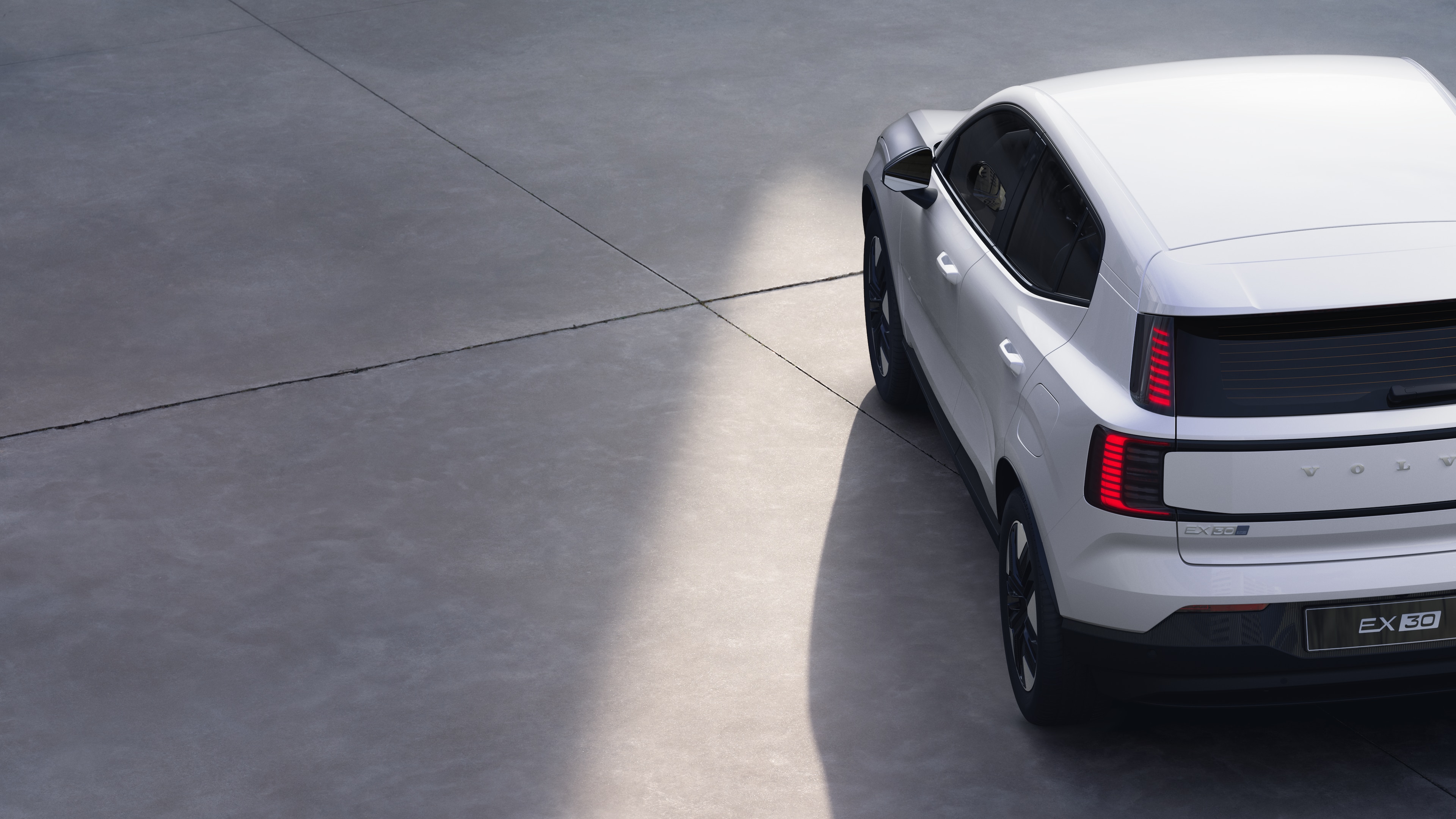 Vue arrière de trois quarts d’une Volvo sur un fond de studio uni, mettant en valeur le design des feux arrière et la structure de la lunette arrière pour les détails extérieurs.