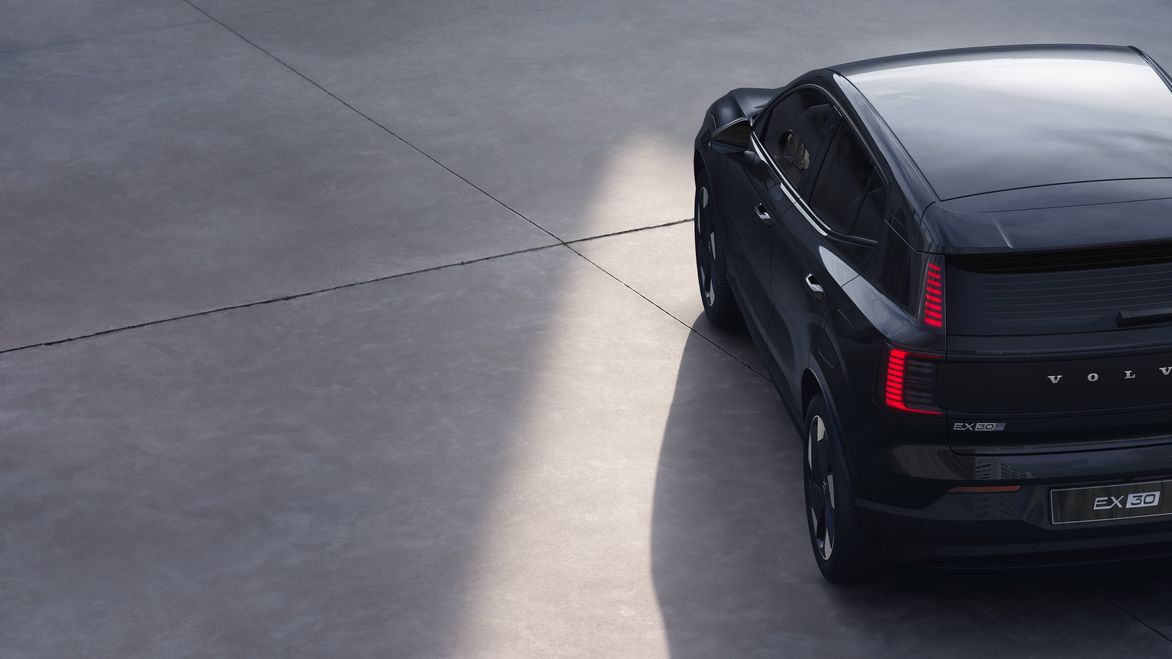 Volvo car three-quarter rear view on plain studio background, showcasing taillight design and rear window structure for exterior detailing.