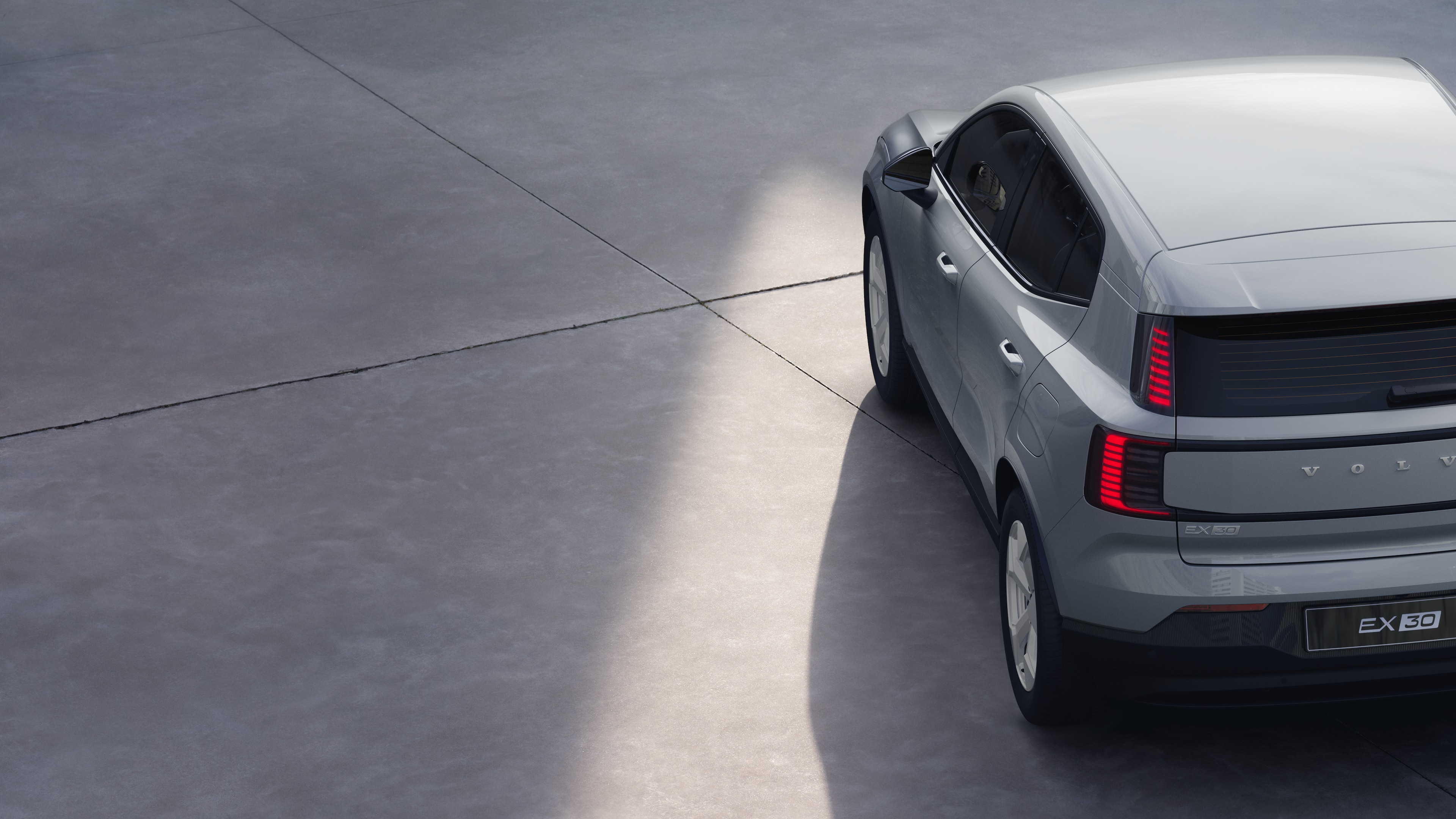 Driekwart achteraanzicht van een Volvo op een effen studioachtergrond, met het ontwerp van de achterlichten en de achterruitstructuur voor details aan de buitenkant.