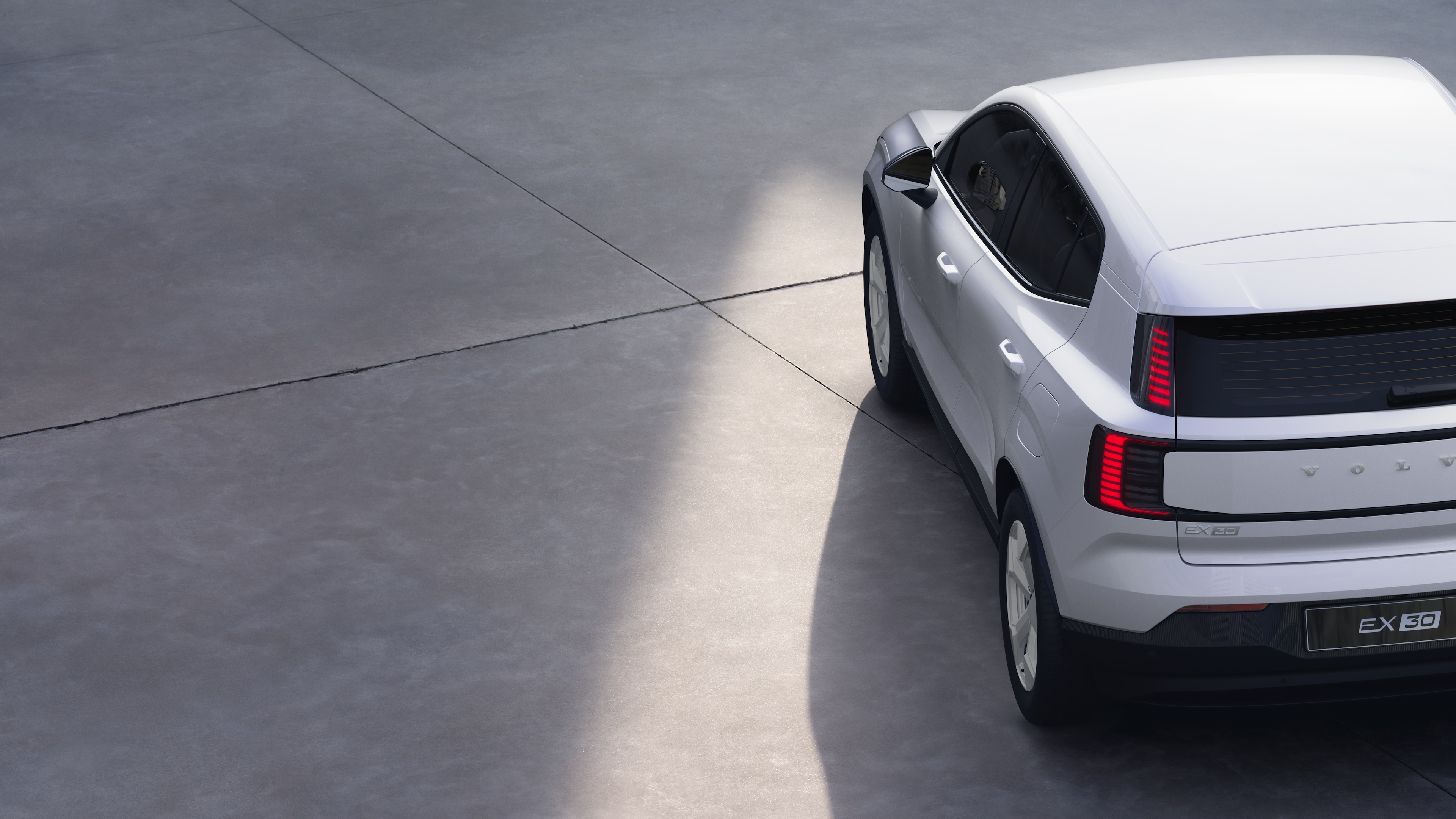 Vista trasera de tres cuartos de un coche Volvo sobre un fondo de estudio liso, que muestra el diseño de las luces traseras y la estructura de la luneta trasera para los detalles exteriores.