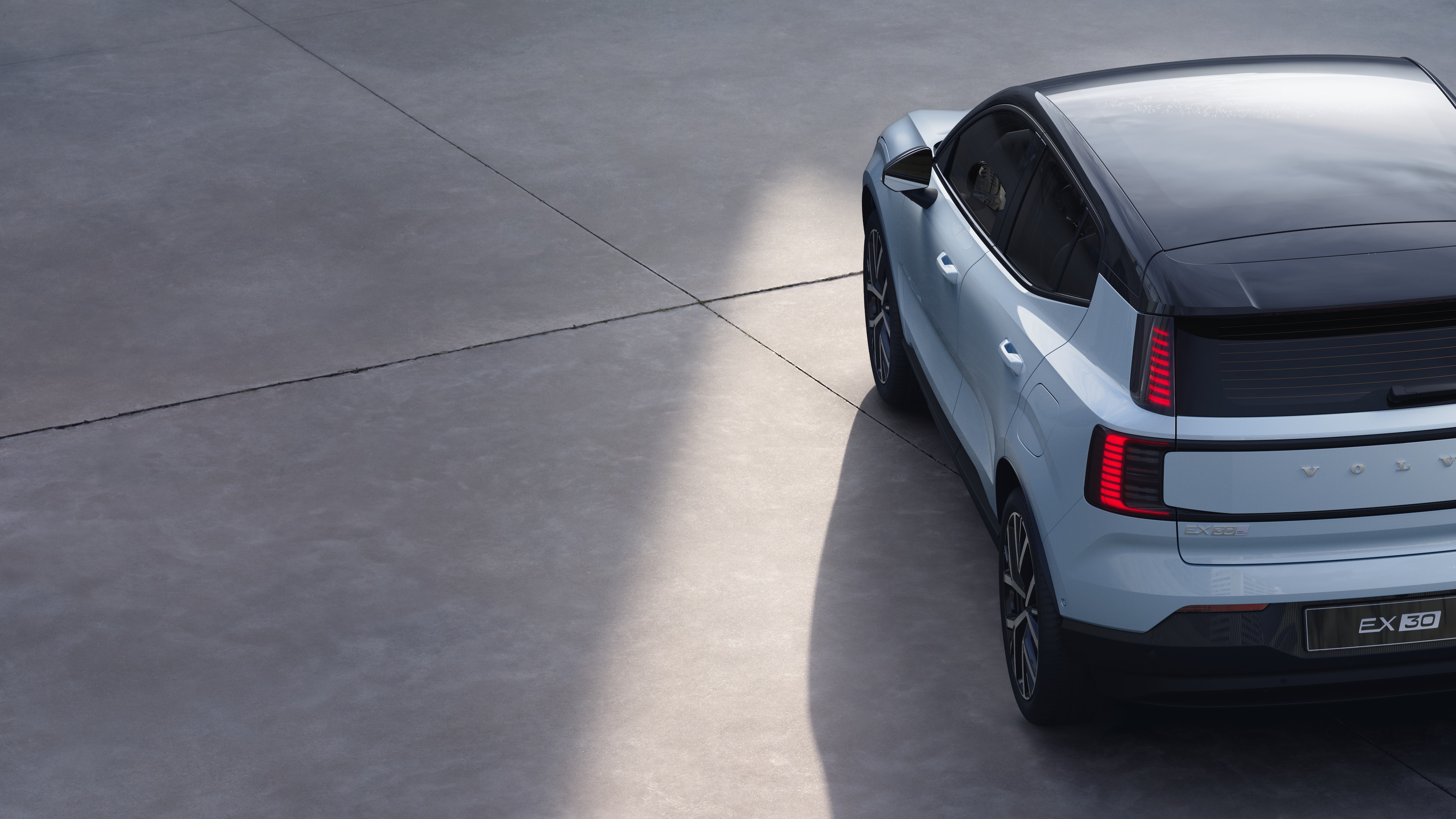 Driekwart achteraanzicht van een Volvo op een effen studioachtergrond, met het ontwerp van de achterlichten en de structuur van de achterruit voor exterieurdetails.