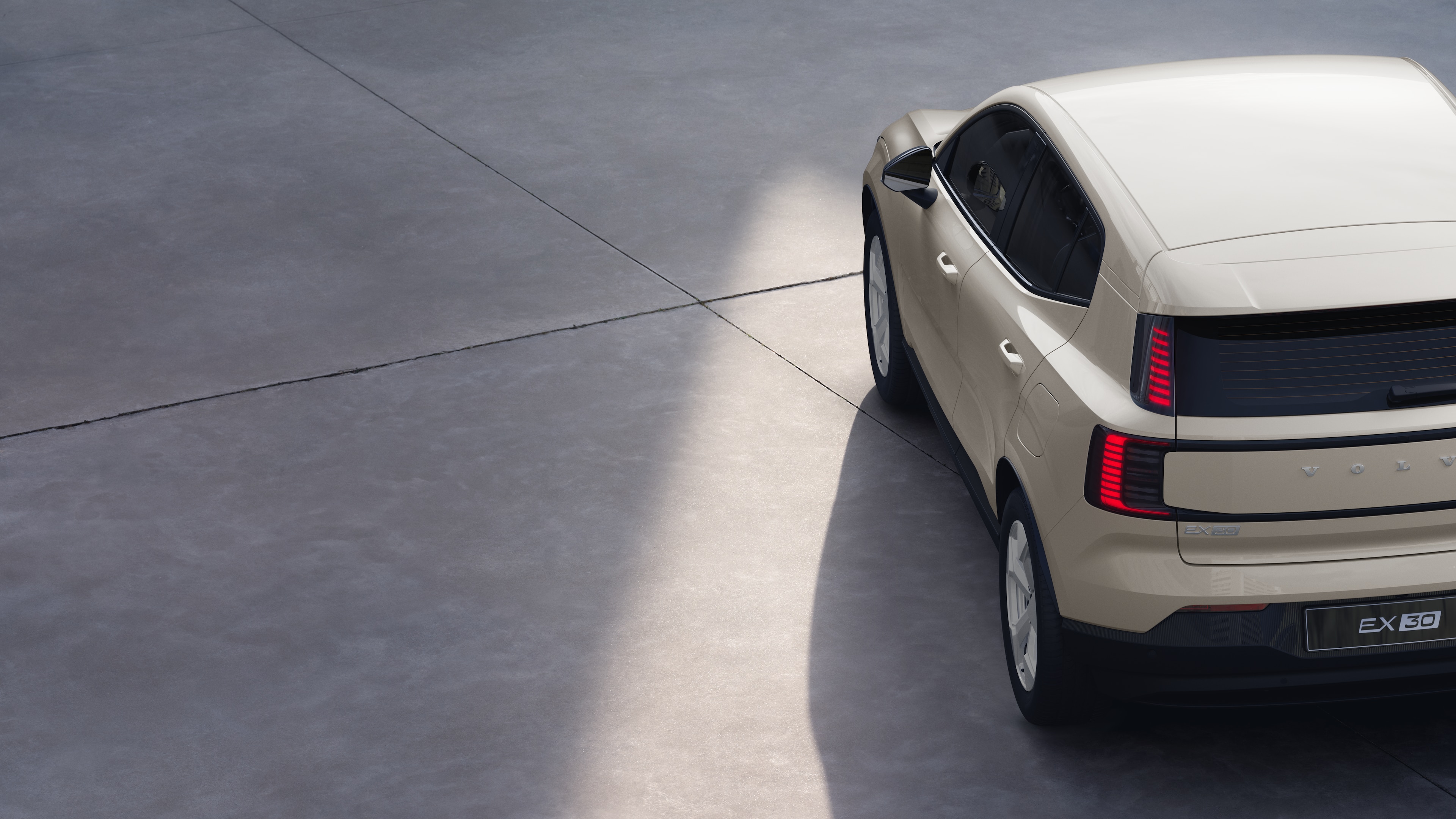 Dreiviertel-Heckansicht eines Volvo-Fahrzeugs auf einem schlichten Studiohintergrund, in dem das Design der Rückleuchten und die Struktur der Heckscheibe für die äußeren Details zu sehen sind.