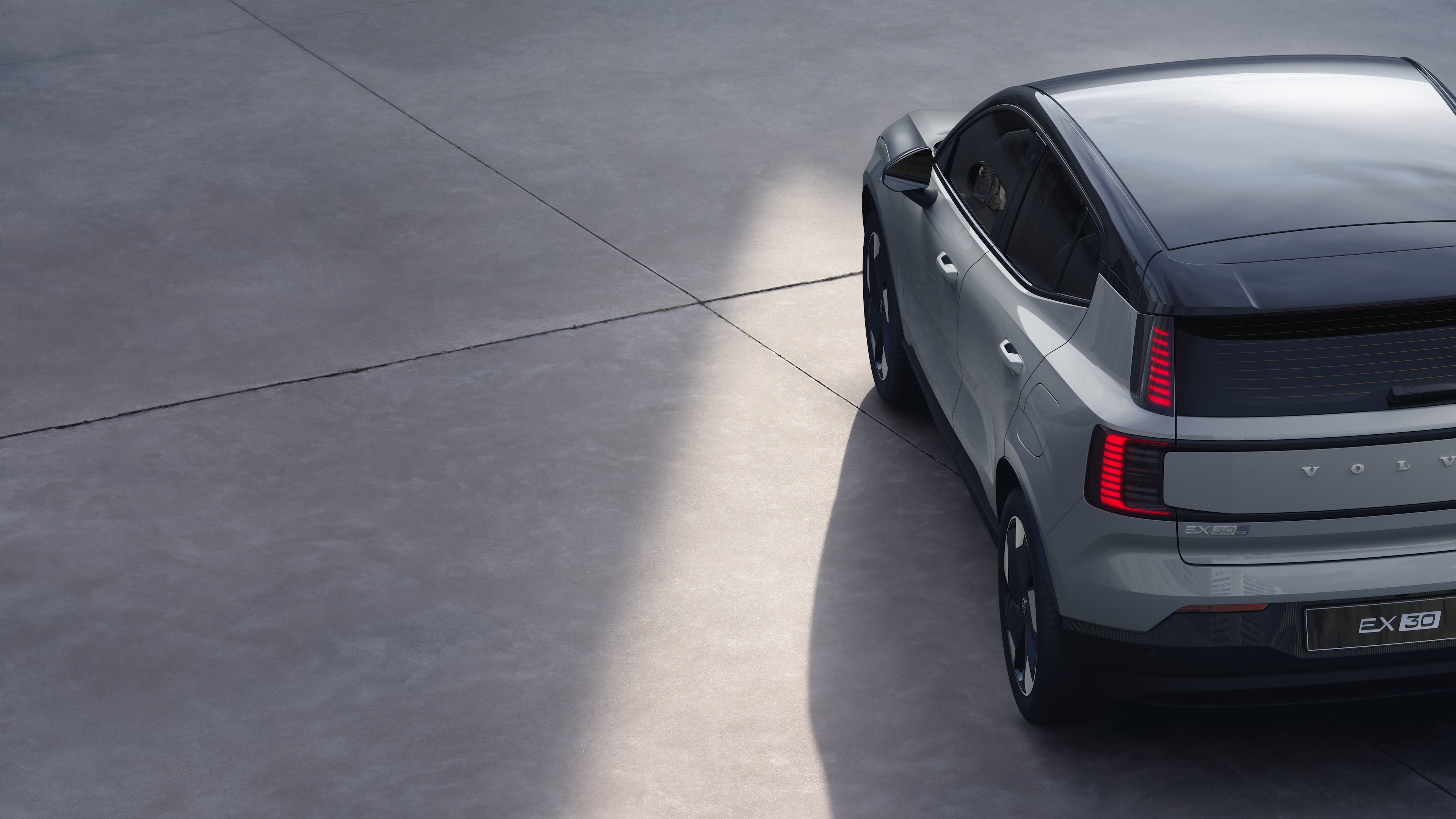 Volvo car three-quarter rear view on plain studio background, showcasing taillight design and rear window structure for exterior detailing.