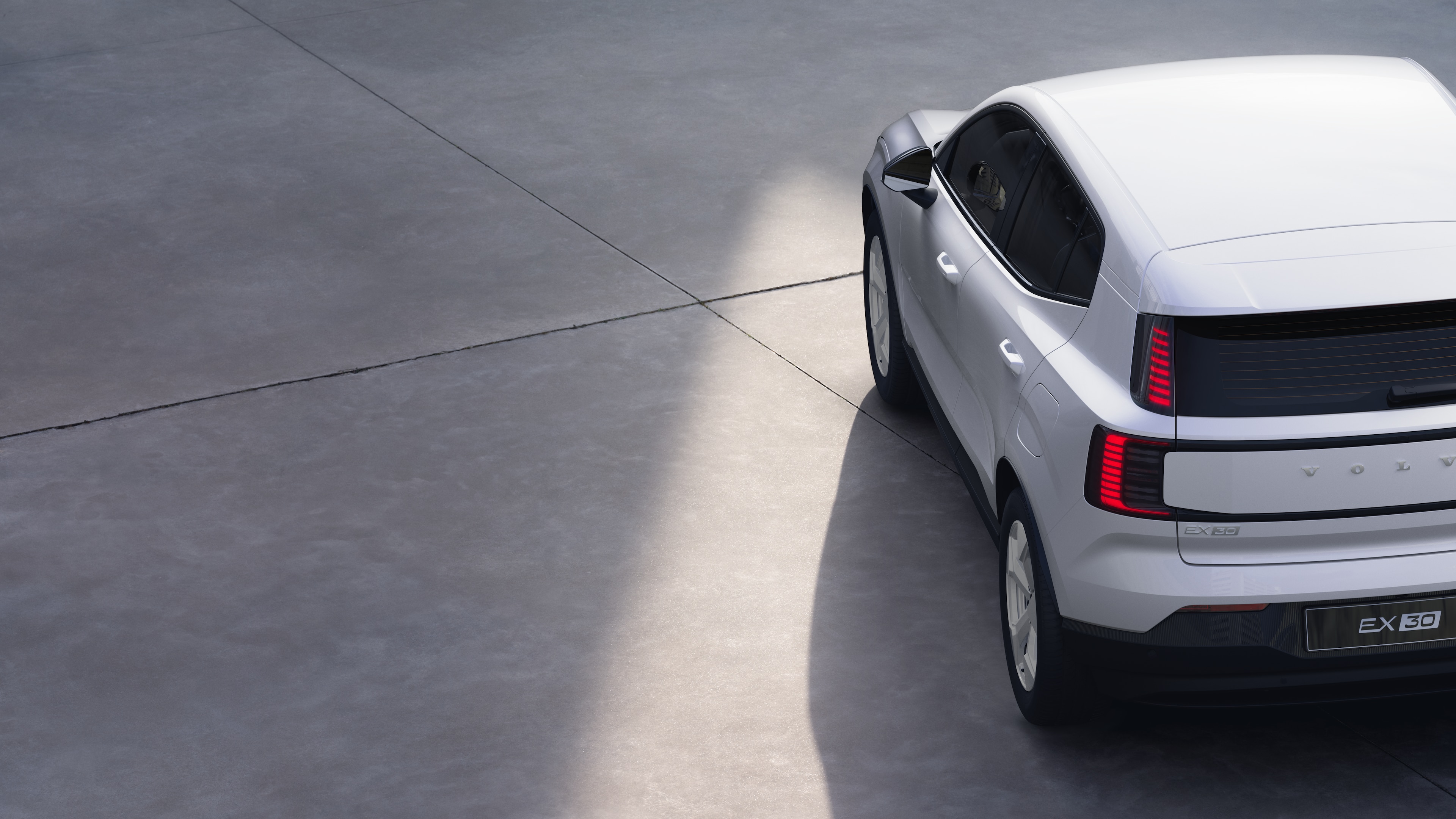 Dreiviertel-Heckansicht eines Volvo-Fahrzeugs auf einem schlichten Studiohintergrund, in dem das Design der Rückleuchten und die Struktur der Heckscheibe für die äußeren Details zu sehen sind.
