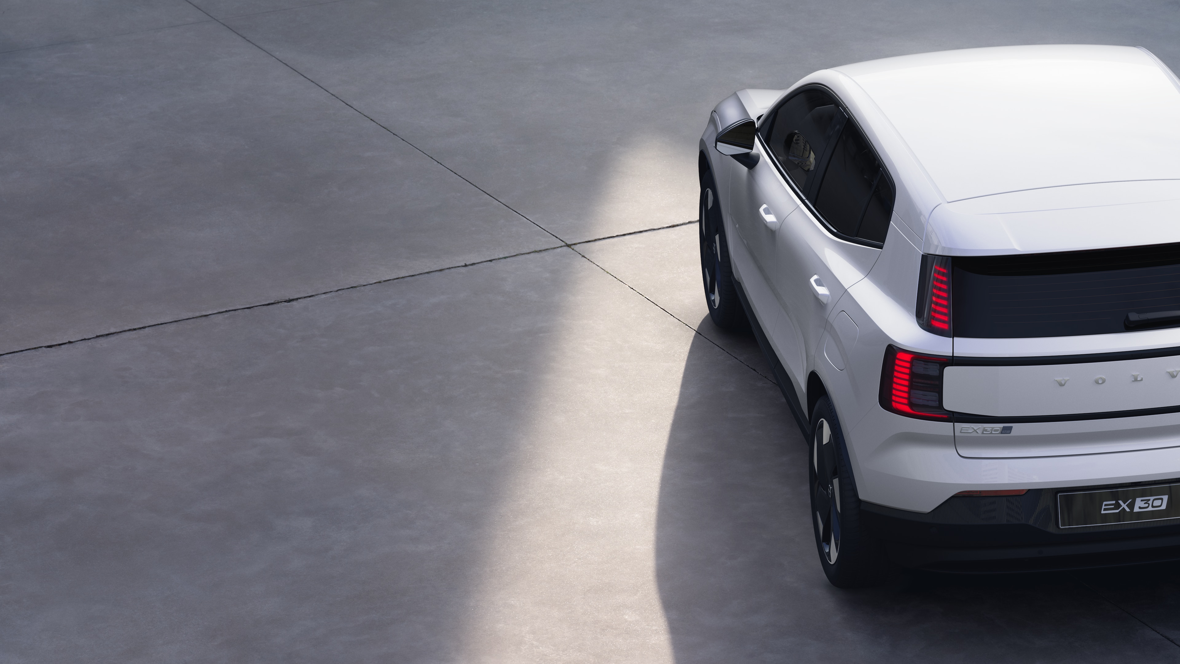 Volvo car three-quarter rear view on plain studio background, showcasing taillight design and rear window structure for exterior detailing.