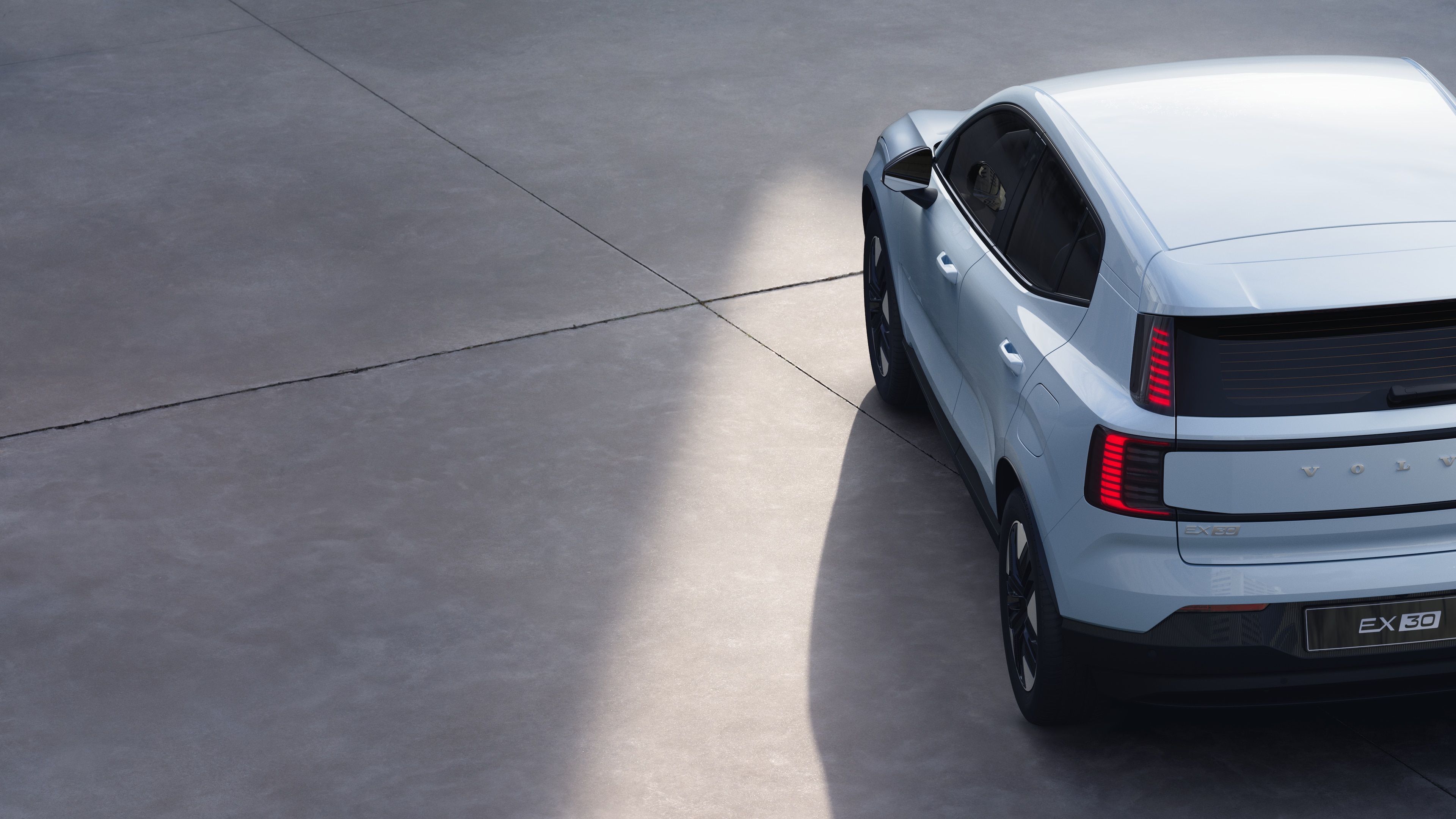 Volvo car three-quarter rear view on plain studio background, showcasing taillight design and rear window structure for exterior detailing.