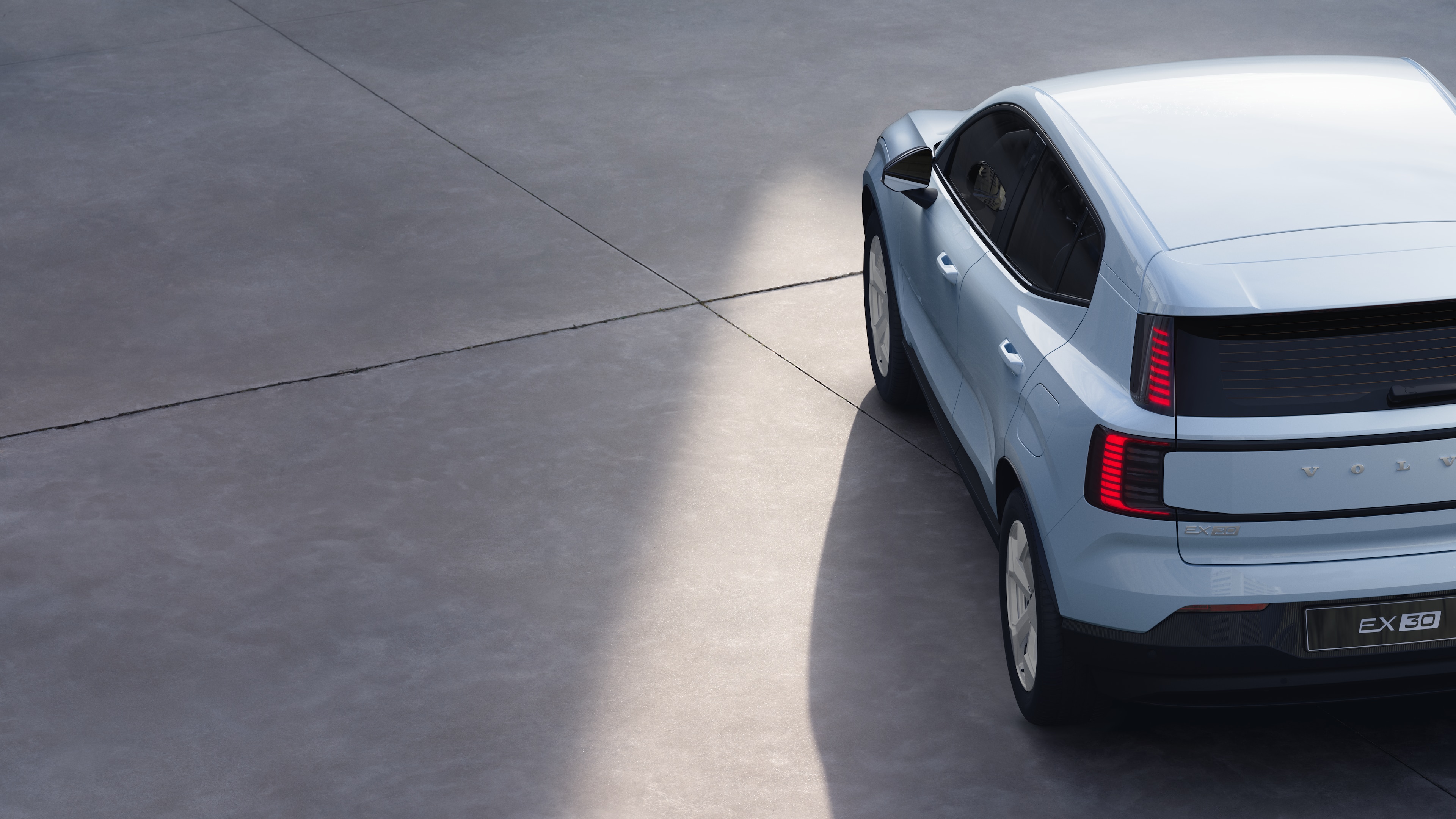 Vista posteriore di tre quarti di un'auto Volvo su uno sfondo in studio, che mostra il design dei fanali posteriori e la struttura del lunotto per i dettagli esterni.