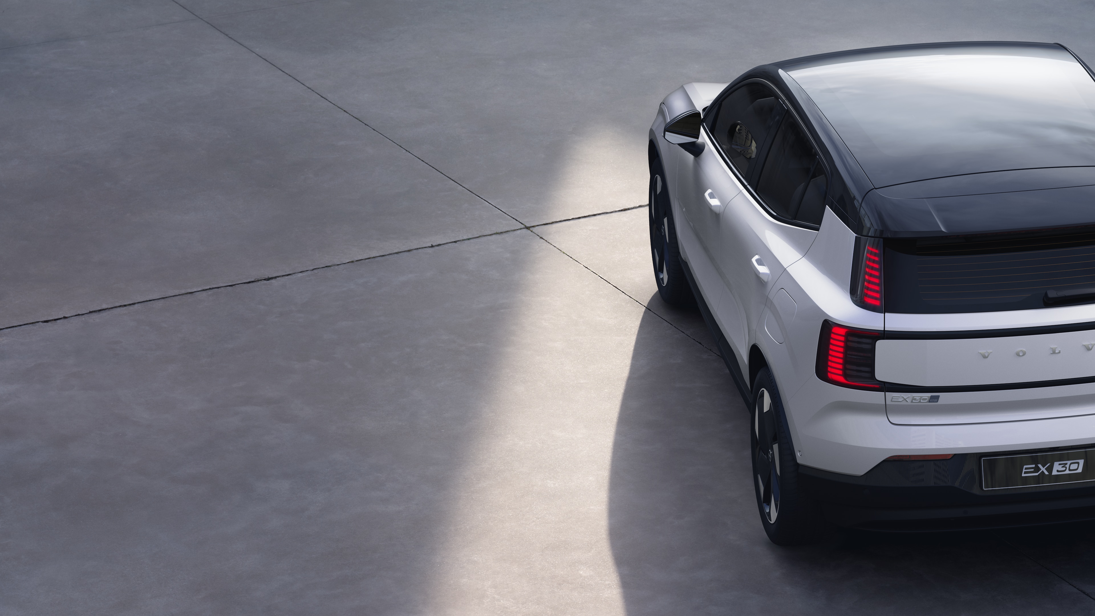 Volvo car three-quarter rear view on plain studio background, showcasing taillight design and rear window structure for exterior detailing.