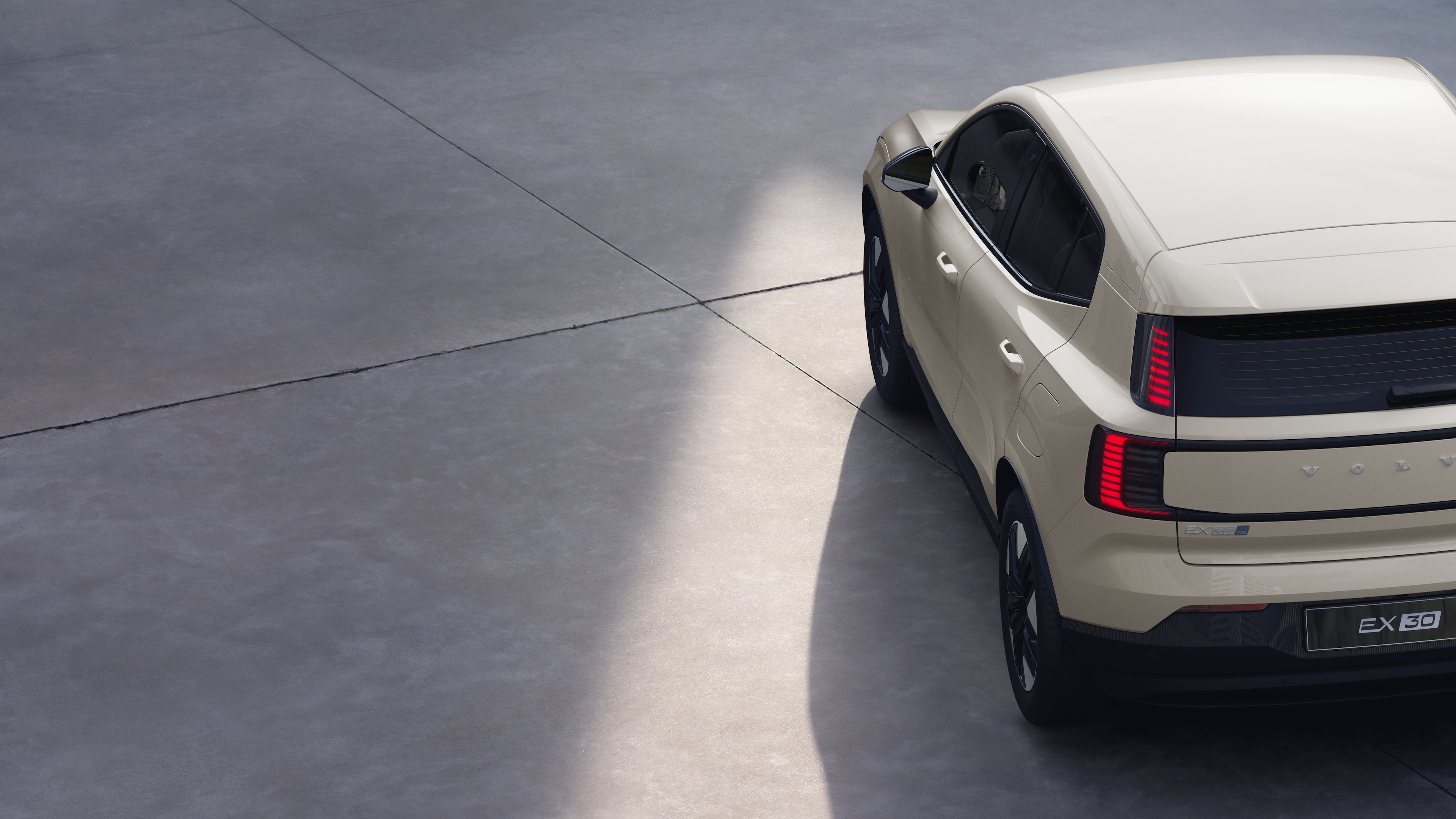 Volvo car three-quarter rear view on plain studio background, showcasing taillight design and rear window structure for exterior detailing.