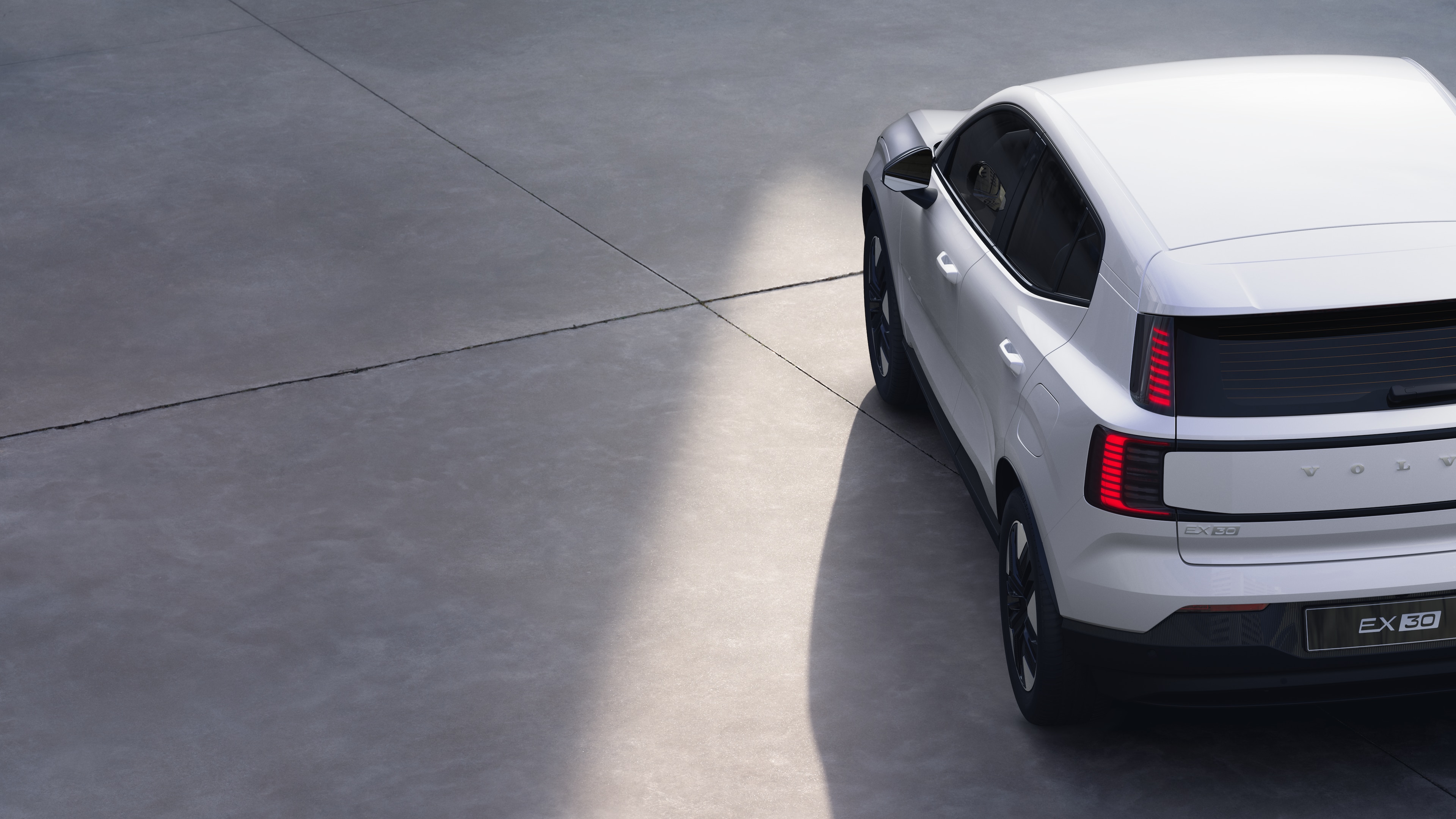 Volvo car three-quarter rear view on plain studio background, showcasing taillight design and rear window structure for exterior detailing.