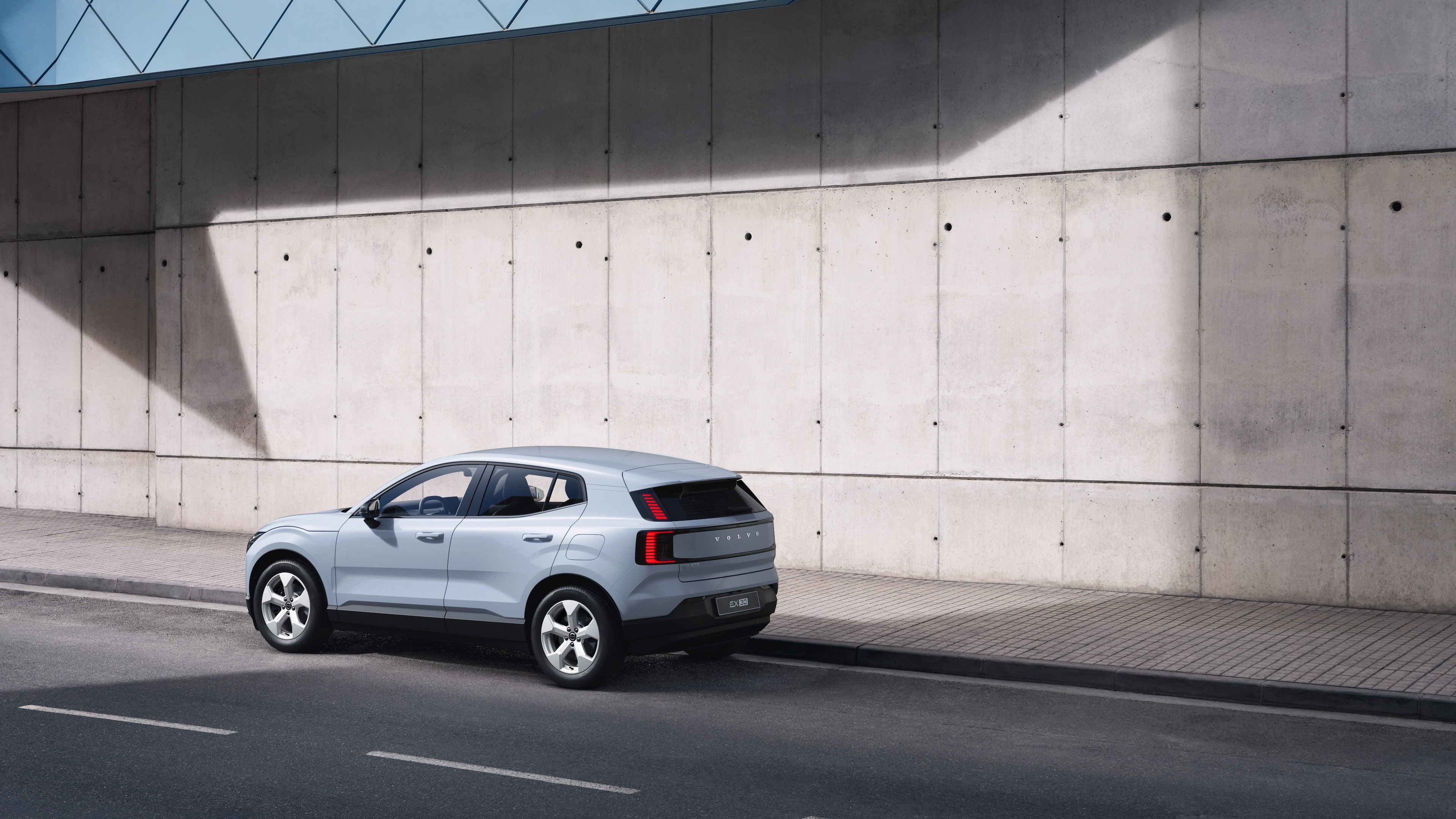 Una Volvo nella vista posteriore di tre quarti parcheggiata contro un muro di cemento sullo sfondo di una strada urbana.