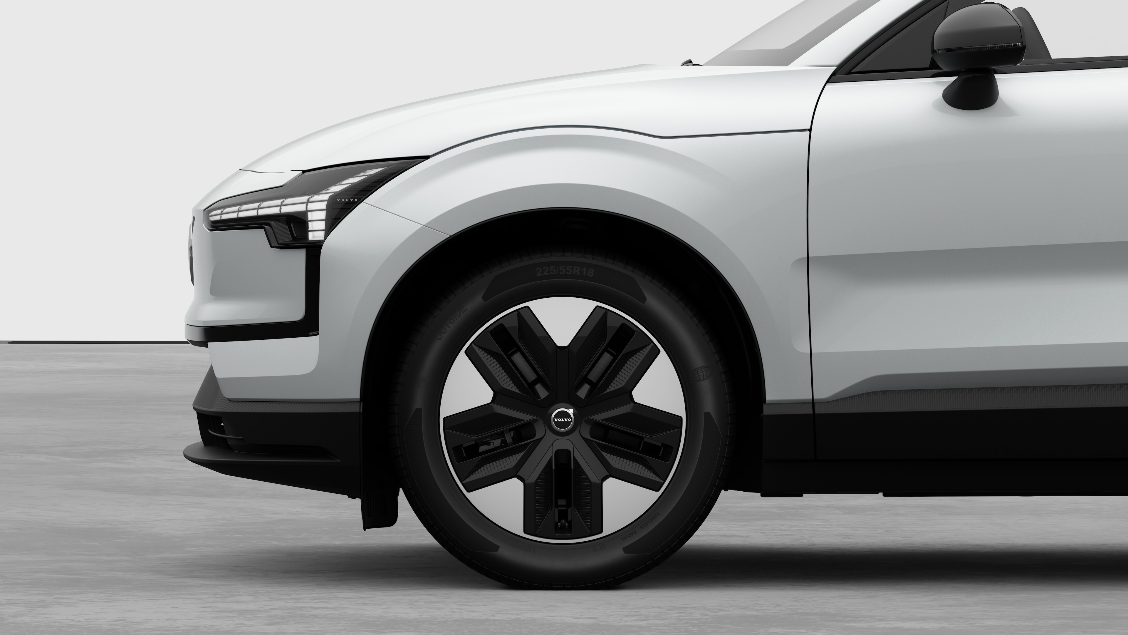 Vista laterale esterna di una Volvo con focus sulla ruota anteriore e sul parafango, su uno sfondo semplice in studio.