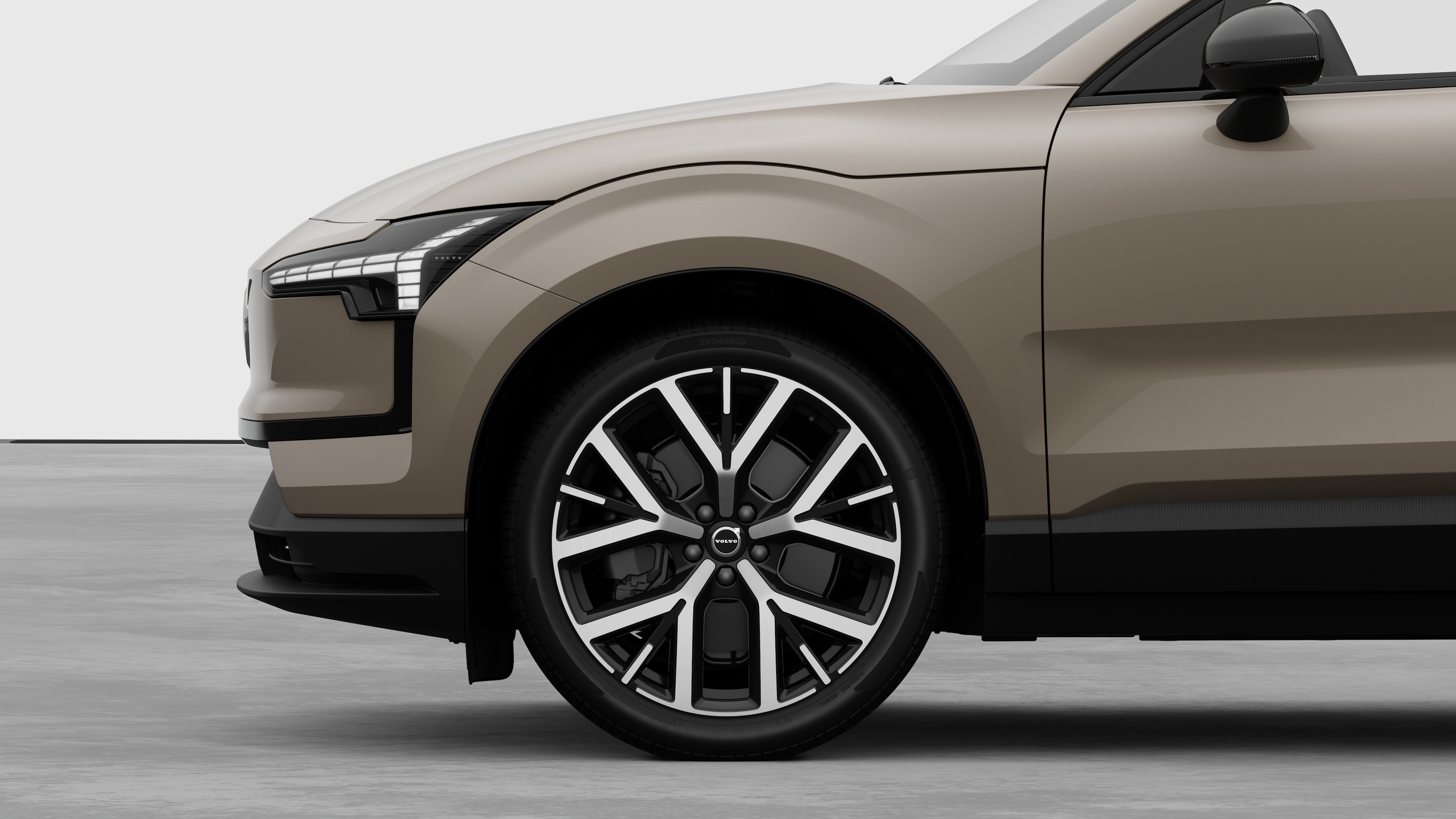 Volvo car exterior side view focusing on the front wheel and fender, set against a plain studio background.