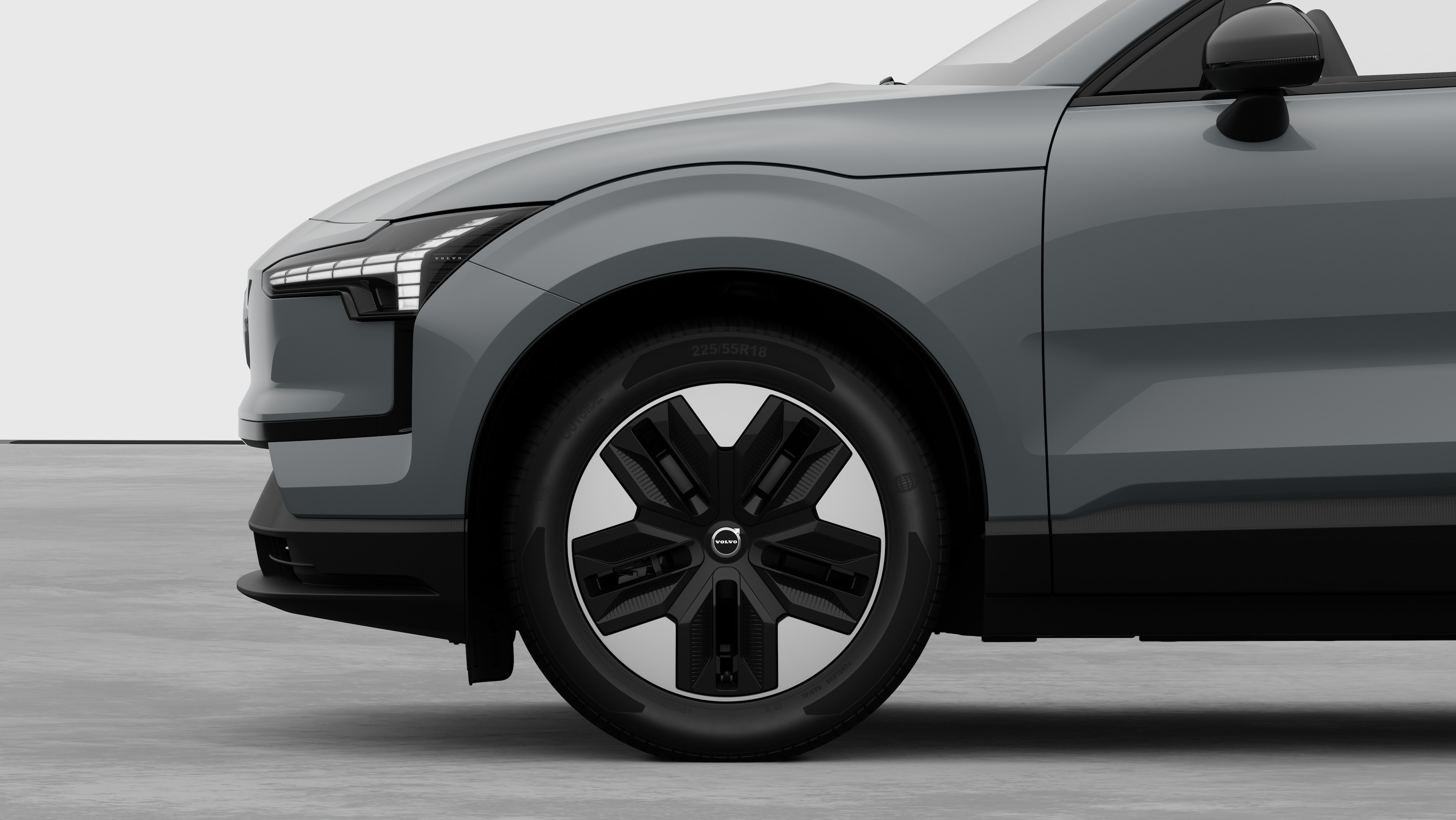 Vista laterale esterna di una Volvo con focus sulla ruota anteriore e sul parafango, su uno sfondo semplice in studio.