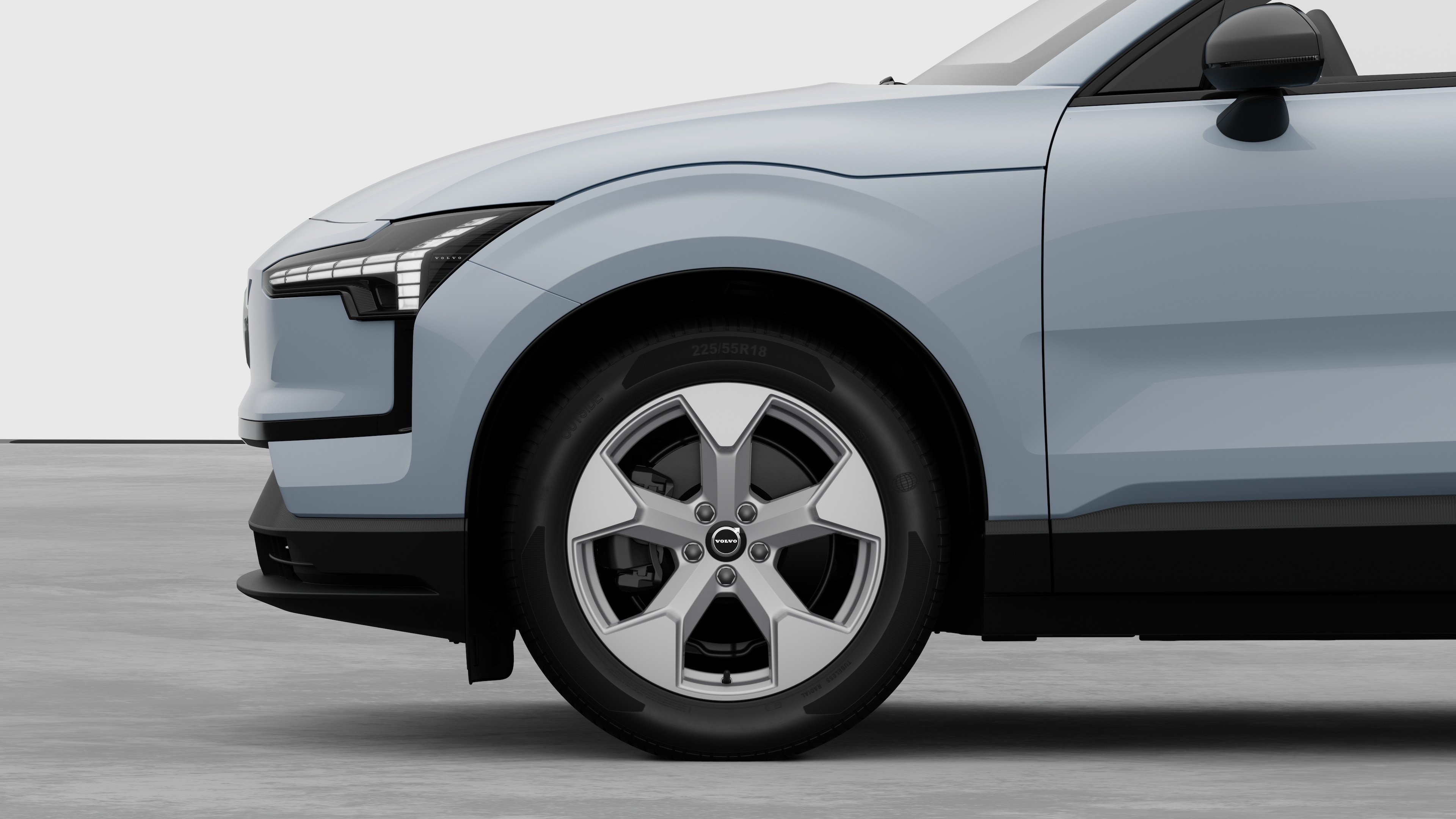 Vista lateral exterior do automóvel Volvo centrada na roda dianteira e no guarda-lamas, contra um fundo de estúdio simples.